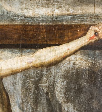 Zdjęcie nr 15: Obraz uzyskał formę stojącego prostokąta zamkniętego łukiem półkolistym nadwieszonym z uskokiem, ujętym w grubą, profilowana i złoconą ramę. W centrum kompozycji przedstawiono grupę Ukrzyżowania. Pod krzyżem, na którym wisi Chrystus stoi Matka Boska i św. Jan Ewangelista. Przybite do krzyża trzema gwoździami ciało Zbawiciela ukazane zostało w lekkim zwisie, o horyzontalnie rozłożonych ramionach. Jego głowa opada na prawe ramię, natomiast korpus wraz z nogami jest wygięty w lewo. Jezus ma wysokie czoło, mocno pociągłą twarz z zamkniętymi oczami, porostym nosem i małymi ustami. Twarz okala krótka, ciemna broda i ciemne włosy, które spływają na prawe ramię. Na głowie widoczna jest korona cierniowa otoczona świetlistymi promieniami. Spod niej ciekną strużki krwi. Jego biodra zakrywa rozwiane, krótkie perizonium z festonem przy prawym boku. Po prawej stronie krzyża wyobrażono Marię w całej postaci, zwróconą w trzech czwartych w prawo, z pochyloną głową i dłońmi skrzyżowanymi na piersi. Madonna ma owalną twarz z dużymi, migdałowatymi oczami zwróconymi ku górze, prosty nos i pełne, rozchylone usta. Wokół głowy widoczny jest nimb. Maria ubrana jest w bladoszkarłatną suknię z widocznymi białymi rękawami spodniej koszuli oraz narzucony na ramiona szaro-niebieski płaszcz z prawą połą przerzuconą przez ręce. Na głowie ma ciemnoochrową chustę owiniętą wokół szyi. Po lewej stronie krzyża ukazano w całej postaci w kontrapoście św. Jan, zwróconego w trzech czwartych w lewo. Apostoł prawą dłonią dotyka piersi, lewą zaś ma odsuniętą od siebie w bok. Jego twarz jest owalna, o dużych, okrągłych oczach, prostym nosie, pełnych ustach, okolona długimi jasnobrązowymi włosami spływającymi na ramiona. Głowę ucznia Jezusa okala nimb. Święty ubrany jest w luźną, ciemnobrązową tunikę oraz długi, fioletowo-brązowy, rozwiany płaszcz. Postacie zostały ukazane na tle pejzażu z widoczną architekturą miasta. W górnej części obrazu widoczne jest ciemne, zachmurzone niebo ze znajdującym się po prawej stronie krzyża zaćmionym słońcem, a po lewo z czerwonym sierpem księżyca. U dołu pionowej belki krzyża widnieje napis: „1695 / R[E]N[OWATUM] / 1703”. Powyżej półkolistego zamknięcia kompozycji w przyłuczach znajduje się ryty w zaprawie i złocony ornament roślinny. 