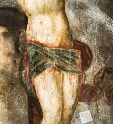 Zdjęcie nr 17: Obraz uzyskał formę stojącego prostokąta zamkniętego łukiem półkolistym nadwieszonym z uskokiem, ujętym w grubą, profilowana i złoconą ramę. W centrum kompozycji przedstawiono grupę Ukrzyżowania. Pod krzyżem, na którym wisi Chrystus stoi Matka Boska i św. Jan Ewangelista. Przybite do krzyża trzema gwoździami ciało Zbawiciela ukazane zostało w lekkim zwisie, o horyzontalnie rozłożonych ramionach. Jego głowa opada na prawe ramię, natomiast korpus wraz z nogami jest wygięty w lewo. Jezus ma wysokie czoło, mocno pociągłą twarz z zamkniętymi oczami, porostym nosem i małymi ustami. Twarz okala krótka, ciemna broda i ciemne włosy, które spływają na prawe ramię. Na głowie widoczna jest korona cierniowa otoczona świetlistymi promieniami. Spod niej ciekną strużki krwi. Jego biodra zakrywa rozwiane, krótkie perizonium z festonem przy prawym boku. Po prawej stronie krzyża wyobrażono Marię w całej postaci, zwróconą w trzech czwartych w prawo, z pochyloną głową i dłońmi skrzyżowanymi na piersi. Madonna ma owalną twarz z dużymi, migdałowatymi oczami zwróconymi ku górze, prosty nos i pełne, rozchylone usta. Wokół głowy widoczny jest nimb. Maria ubrana jest w bladoszkarłatną suknię z widocznymi białymi rękawami spodniej koszuli oraz narzucony na ramiona szaro-niebieski płaszcz z prawą połą przerzuconą przez ręce. Na głowie ma ciemnoochrową chustę owiniętą wokół szyi. Po lewej stronie krzyża ukazano w całej postaci w kontrapoście św. Jan, zwróconego w trzech czwartych w lewo. Apostoł prawą dłonią dotyka piersi, lewą zaś ma odsuniętą od siebie w bok. Jego twarz jest owalna, o dużych, okrągłych oczach, prostym nosie, pełnych ustach, okolona długimi jasnobrązowymi włosami spływającymi na ramiona. Głowę ucznia Jezusa okala nimb. Święty ubrany jest w luźną, ciemnobrązową tunikę oraz długi, fioletowo-brązowy, rozwiany płaszcz. Postacie zostały ukazane na tle pejzażu z widoczną architekturą miasta. W górnej części obrazu widoczne jest ciemne, zachmurzone niebo ze znajdującym się po prawej stronie krzyża zaćmionym słońcem, a po lewo z czerwonym sierpem księżyca. U dołu pionowej belki krzyża widnieje napis: „1695 / R[E]N[OWATUM] / 1703”. Powyżej półkolistego zamknięcia kompozycji w przyłuczach znajduje się ryty w zaprawie i złocony ornament roślinny. 