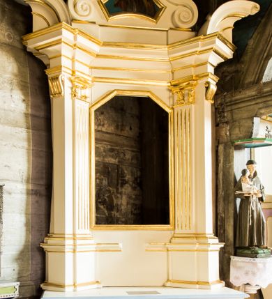 Zdjęcie nr 1: Jednokondygnacyjna i jednoosiowa nastawa ołtarza bocznego uzyskała formę architektoniczną ze zwieńczeniem, ustawioną na cokole. Stipes ołtarzowy ustawiony na podeście uzyskał kształt sarkofagu malowanego na czerwono o linii wklęsło-wypukłej z profilowanym cokołem i gzymsem pomalowanych na bladoniebiesko. W narożach stipesu dekorację wykonano na zielono w geometryczne wzory. W centrum pola umieszczono malowany chrystogram "IHS" na niebieskim tle otoczony wieńcem z kwiatów. Nastawa została ujęta parą opilastrowanych filarów, ustawionych pod kątem, zwróconych na zewnątrz, dźwigających pełne belkowanie przerwane nad polem środkowym oraz fragmenty przerwanego odwróconego przyczółka. Trzony wewnętrznych pilastrów o głowicach korynckich są kanelowane. W polu głównym znajduje się prześwit w formie stojącego prostokąta zamkniętego trójbocznie. Pilastry zewnętrzne u szczytu zwieńczono złoconymi wolutami. Zwieńczenie uzyskało formę trapezu o wklęsłych bokach zakończonego półkoliście wygiętym gzymsem, przechodzącym po bokach w woluty. Na wolutach widoczne są liście palmowe. W polu umieszczono obraz św. Erazma w profilowanej ramie w formie zbliżonej do trapezu o wklęsłych bokach i ściętych dolnych narożach, zamkniętego łukiem falistym. Struktura nastawy została polichromowana w kolorze kości słoniowej, ze złoconymi profilami i ornamentami.


