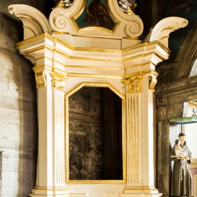 Zdjęcie nr 1: Jednokondygnacyjna i jednoosiowa nastawa ołtarza bocznego uzyskała formę architektoniczną ze zwieńczeniem, ustawioną na cokole. Stipes ołtarzowy ustawiony na podeście uzyskał kształt sarkofagu malowanego na czerwono o linii wklęsło-wypukłej z profilowanym cokołem i gzymsem pomalowanych na bladoniebiesko. W narożach stipesu dekorację wykonano na zielono w geometryczne wzory. W centrum pola umieszczono malowany chrystogram "IHS" na niebieskim tle otoczony wieńcem z kwiatów. Nastawa została ujęta parą opilastrowanych filarów, ustawionych pod kątem, zwróconych na zewnątrz, dźwigających pełne belkowanie przerwane nad polem środkowym oraz fragmenty przerwanego odwróconego przyczółka. Trzony wewnętrznych pilastrów o głowicach korynckich są kanelowane. W polu głównym znajduje się prześwit w formie stojącego prostokąta zamkniętego trójbocznie. Pilastry zewnętrzne u szczytu zwieńczono złoconymi wolutami. Zwieńczenie uzyskało formę trapezu o wklęsłych bokach zakończonego półkoliście wygiętym gzymsem, przechodzącym po bokach w woluty. Na wolutach widoczne są liście palmowe. W polu umieszczono obraz św. Erazma w profilowanej ramie w formie zbliżonej do trapezu o wklęsłych bokach i ściętych dolnych narożach, zamkniętego łukiem falistym. Struktura nastawy została polichromowana w kolorze kości słoniowej, ze złoconymi profilami i ornamentami.


