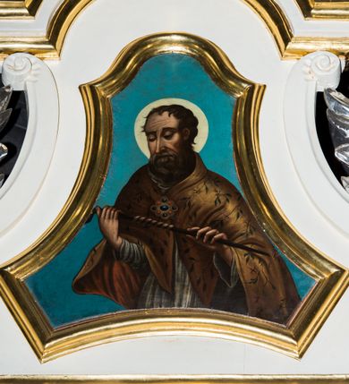 Zdjęcie nr 2: Jednokondygnacyjna i jednoosiowa nastawa ołtarza bocznego uzyskała formę architektoniczną ze zwieńczeniem, ustawioną na cokole. Stipes ołtarzowy ustawiony na podeście uzyskał kształt sarkofagu malowanego na czerwono o linii wklęsło-wypukłej z profilowanym cokołem i gzymsem pomalowanych na bladoniebiesko. W narożach stipesu dekorację wykonano na zielono w geometryczne wzory. W centrum pola umieszczono malowany chrystogram "IHS" na niebieskim tle otoczony wieńcem z kwiatów. Nastawa została ujęta parą opilastrowanych filarów, ustawionych pod kątem, zwróconych na zewnątrz, dźwigających pełne belkowanie przerwane nad polem środkowym oraz fragmenty przerwanego odwróconego przyczółka. Trzony wewnętrznych pilastrów o głowicach korynckich są kanelowane. W polu głównym znajduje się prześwit w formie stojącego prostokąta zamkniętego trójbocznie. Pilastry zewnętrzne u szczytu zwieńczono złoconymi wolutami. Zwieńczenie uzyskało formę trapezu o wklęsłych bokach zakończonego półkoliście wygiętym gzymsem, przechodzącym po bokach w woluty. Na wolutach widoczne są liście palmowe. W polu umieszczono obraz św. Erazma w profilowanej ramie w formie zbliżonej do trapezu o wklęsłych bokach i ściętych dolnych narożach, zamkniętego łukiem falistym. Struktura nastawy została polichromowana w kolorze kości słoniowej, ze złoconymi profilami i ornamentami.


