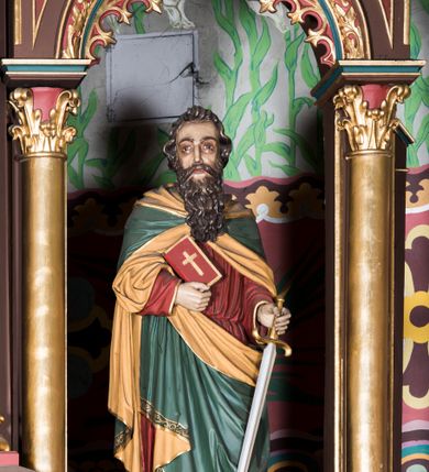 Zdjęcie nr 11: Ołtarz główny uzyskał formę architektonicznej struktury przyściennej, trójosiowej i jednokondygnacyjnej ze zwieńczeniem. Stipes ołtarzowy przyjął formę stołu, gdzie mensę z portatylem wsparto na czterech kolumnach ustawionych na wysokich wielobocznych bazach. Pomiędzy nimi usytuowano płaskorzeźbioną sceną Ostatniej Wieczerzy w kształcie leżącego prostokąta. Na mensie w osi ołtarza ustawione zostało tabernakulum z tronem wystawienia w kształcie baldachimu, stanowiące cześć środkową architektonicznego, trójosiowego założenia, gdzie w osiach bocznych w półokrągłych aediculach z wimpergami ustawiono parę adorujących aniołów. Nastawa ustawiona na wysokim cokole została dekorowana profilowanymi płycinami, ponad którymi poprowadzono profilowanym gzyms. Oś środkowa retabulum została ujęta złoconymi kolumnami o korynckich kapitelach i gładkich trzonach. Kolumny dźwigają półkoliście zamkniętą arkadę zwieńczoną profilowanym gzymsem z trójkątnie zakończoną wimpergą ozdobioną żabkami. Zwieńczenie utworzono w formie ażurowej kapliczki na rzucie wieloboku mieszczącej pełnoplastyczną figurę Michała Archanioła trzymającego miecz i wagę. Kapliczkę zakończono wieloboczną fialą o ściankach zdobionych ślepymi maswerkami. W osiach skrajnych wykonano analogiczne arkady wsparte na złoconych kolumnach mieszczące figury św. Piotra (z lewej) i św. Pawła (z prawej). W zwieńczeniach w osi znalazły się w ażurowych kapliczkach zakończonych fialami pełnoplastyczne figury św. Wojciecha i św. Stanisława w strojach pontyfikalnych. W polu ołtarza usytuowano obraz przedstawiający wszystkich świętych adorujących Trójcę Przenajświętszą. Pole ujmuje płaskorzeźbiona, złocona rama z dekoracją akantową zamknięta łukiem trójlistnym. W podłuczu wykonano arkaturę. Na zasuwie umieszczono obraz Najświętszego Serca Pana Jezusa. W płycinach wypełniających elementy architektoniczne znalazła się stylizowana dekoracja akantowa oraz motyw czwórliścia wpisanego w okrąg. Struktura ołtarza została polichromowana w odcieniach zgaszonej czerwieni i złamanego brązu wchodzącego w fiolet. Ornamentyka oraz detale elementów i profilów architektonicznych wyzłocono.