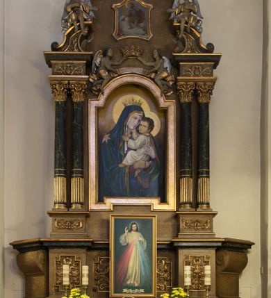 Zdjęcie nr 1: Jednokondygnacyjny, jednoosiowy ołtarz przyścienny ze zwieńczeniem uzyskał strukturę architektoniczną. Stipes ołtarzowy wykonano w formie wklęsło-wypukłego sarkofagu, zwężającego się ku dołowi, ujętego akantowymi wolutami. Na jego licu w centrum umieszczono płaskorzeźbiony medalion z monogramem maryjnym, ujęty symetryczną dekoracją roślinną, utworzoną z wici akantu oraz kwiatów. Retabulum zostało ustawione na wysokim, dwudzielnym cokole. Cokół zwieńczony profilowanym gzymsem udekorowano płycinami, które w wyższej kondygnacji wypełnione zostały dekoracją akantową. Nastawa po bokach ujęta została zdwojonymi kolumnami, umieszczonymi na prostopadłościennych postumentach z  symetryczną dekoracją utworzoną z akantu i kwiatów. Kapitele kolumn są kompozytowe, zaś trzony do jednej trzeciej wysokości zdobione zostały kanelurami. Kolumny podtrzymują odcinki pełnego belkowania, na których umieszczone są odcinki przerwanego przyczółka z umieszczonymi na nich figurami aniołów. Zwieńczenie ma formę zbliżoną do prostokąta zamkniętego od góry antytetycznie ustawionymi wolutami. Pomiędzy nimi na osi umieszczono na tle glorii promienistej złocony krzyż o trójlistnie zakończonych ramionach. W polu ołtarza usytuowano płycinę zamkniętą łukiem nadwieszonym z obrazem Matki Boskiej Szkaplerznej z Dzieciątkiem. Ponad obrazem znalazły się dwie rzeźbione figury aniołów podtrzymujących koronę oraz złoconą banderole z napisem: &quot;ZDROWAŚ  MARIO&quot;. W zwieńczeniu umieszczono obraz św. Floriana w kształcie stojącego prostokąta o wklęsłych bokach, ściętych narożach i zamkniętego łukiem wklęsło-wypukłym. Struktura ołtarza została polichromowana w odcieniach brązu i czerni, natomiast ornamentykę i detale architektoniczne wyzłocono.