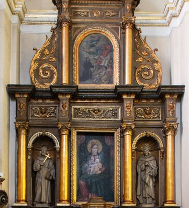 Zdjęcie nr 1: Dwukondygnacyjny, trójosiowy ołtarz przyścienny ze zwieńczeniem uzyskał strukturę architektoniczną. Stipes ołtarzowy wykonano w formie stołu z mensą wspartą na dwóch parach filarów z kanelurą zwężających się ku dołowi,  ustawionych na postumentach z przodu i z tyłu. Pomiędzy tylnią parą wprowadzono płycinę w kształcie leżącego prostokąta. W jej pole wpisano płaskorzeźbiony krzyż równoramienny w czteroliściu obramieniony profilowanymi ramkami. Nastawę ołtarza umieszczona na wysokim cokole, zwieńczonym profilowanym gzymsem. Na osi na mensie ustawiono architektoniczne tabernakulum, ujęte ustawionymi ukośnie kolumienkami, dźwigającymi odcinki pełnego belkowania, zwieńczone daszkiem w kształcie ściętego ostrosłupa z tronem wystawienia. Na drzwiczkach namalowano kielich z hostią w złoconej płycinie. Powyżej drzwiczek ukazano płaskorzeźbioną, uskrzydloną główkę aniołka. Nastawa została artykułowana kompozytowymi kolumnami o gładkich, złoconych trzonach, ustawionymi na występujących przed lico ołtarza prostopadłościennych postumentach, dekorowanych  płaskorzeźbionymi festonami. Kolumny dolnej kondygnacji podtrzymują pełne belkowanie z rozbudowanym fryzem, dekorowanym płycinami, wypełnionymi wicią akantową, kwiatami oraz uskrzydlonymi główkami anielskimi. Belkowanie wieńczy rozbudowany, silnie wystający, profilowany gzyms. Także kondygnację drugą ujęto parą kolumn analogicznych jak w kondygnacji pierwszej, a po bokach zamknięto ją akantowymi spływami wolutowymi. Kolumny podtrzymują pełne belkowanie z fryzem dekorowanym kartuszami, rozetą, kwiatami oraz profilowany gzyms. Zwieńczenie retabulum wykonano w formie przerwanego przyczółka o linii łuku odcinkowego z umieszczonym na osi złoconym krzyżem na tle glorii promienistej. W kondygnacji pierwszej w osi środkowej znalazła się prostokątna płycina mieszcząca obraz Matki Boskiej z Dzieciątkiem. W osiach skrajnych usytuowano zamknięte półkoliście nisze, dekorowane muszlą palmetową, mieszczące pełnoplastyczne figury. Z lewej ustawiono rzeźbę św. Franciszka, a z prawej św. Dominika. Także w kondygnacji drugiej umieszczono na osi płycinę w kształcie stojącego prostokąta zamkniętą półkoliście, w której zainstalowano obraz przedstawiający wizję św. Franciszka. Ołtarz został polichromowany w odcieniach brązu, natomiast ornamentykę i detale architektoniczne pozłocono.