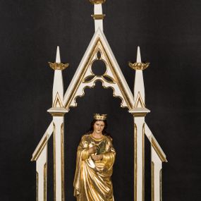 Zdjęcie nr 1: Na prostopadłościennej podstawie przeprutej otworami umożliwiającymi zakładzie drążków do noszenia ustawiono ażurowe obramienie ujmujące pełnoplastyczną rzeźbę św. Barbary. Bok podstawy zdobi złocony ornament liściasto-roślinny. Świętą ustawiono na czworobocznym postumencie. Jest to młoda kobieta ukazana frontalnie w kontrapoście. Lewą rękę przyciska do piersi, w prawej trzyma gałązkę palmową. Barbara ma pociągłą twarz o jasnej karnacji, prostym nosie i wąskich ustach. Jej głowę okalają długie włosy spływające na ramiona. Na głowie ma złoconą, otwartą koronę o prostych sterczynach. Ubrana jest w długą suknię i mocno drapowany płaszcz okrywający jej postać. Rozpięte ponad nią obramienie utworzono z wimpergi dekorowanej arkaturą i stylizowanym maswerkiem w części górnej, zwieńczoną pinaklem z kwiatonem. Wspiera się ona na dwóch wielobocznych filarach wspartych na cokolikach i przechodzących w dwa pinakle z kwiatonami. Oba filary po bokach wspierają przypory w formie podobnych, wielobocznych filarków na cokolikach u góry połączonych z resztą konstrukcji za pomocą daszków pulpitowych. Całość struktury feretronu polichromowano na biało, profile i kwiatony zostały pozłocone. 