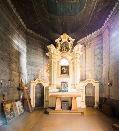 Zdjęcie nr 15: Kościół stanowi orientowaną, drewnianą świątynie wzniesioną na zrąb w układzie salowym z nawą na rzucie zbliżonym do kwadratu. Od wschody do nawy przylega węższe, prostokątne prezbiterium zamknięte trójbocznie. Od północy do prezbiterium dostawiono drewnianą zakrystię połączoną za pomocą portalu z prezbiterium kościoła. Do nawy od zachodu dostawiono czworoboczną wieżę o pochyłych ścianach, wzniesioną w konstrukcji słupowej. Wieńczy ją nadwieszona, czworoboczna izbica z ostrosłupowym, gontowym hełmem z krzyżem. W przyziemiach wieży urządzono kruchtę połączoną z nawą świątyni. Od północy, wschodu i południa kościół otaczają otwarte soboty, szalowane przy wieży. Elewacje zewnętrze zostały oszalowane lub też pokryte gontem. W nawie i prezbiterium przepruto okna parzyste, czworoboczne. Całość nakrywa dach gontowy o jednej kalenicy. Nad nawą w części wschodniej nadwieszono wieloboczną sygnaturkę w formie latarni z baniastym hełmem. Wnętrze nakryto stropami, dodatków w nawie z zaskrzynieniami. Pomiędzy prezbiterium, a nawą rozpięta jest ostrołukowa tęcza z fazowaną belką zawieszoną na kroksztynach z ustawionym na osi krucyfiksem. W zachodniej części nawy urządzono chór muzyczny o drewnianym, pełnym parapecie wklęsło-wypukłym z lambrekinem, wspartym na dwóch żłobkowanych kolumnach. Odrzwia południowe prowadzące do nawy ujęto w portal wycięty w ośli grzbiet. W prezbiterium ustawiono ołtarz główny, a w nawie dwa ołtarze boczne. 