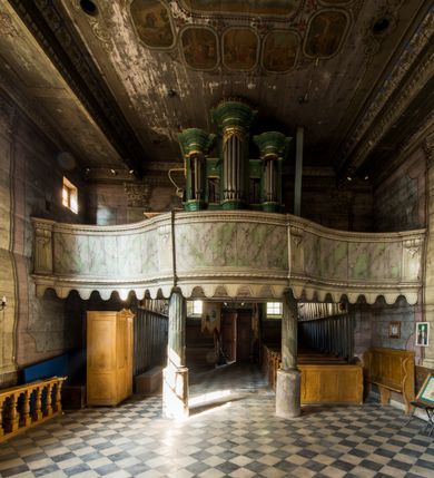 Zdjęcie nr 7: Kościół stanowi orientowaną, drewnianą świątynie wzniesioną na zrąb w układzie salowym z nawą na rzucie zbliżonym do kwadratu. Od wschody do nawy przylega węższe, prostokątne prezbiterium zamknięte trójbocznie. Od północy do prezbiterium dostawiono drewnianą zakrystię połączoną za pomocą portalu z prezbiterium kościoła. Do nawy od zachodu dostawiono czworoboczną wieżę o pochyłych ścianach, wzniesioną w konstrukcji słupowej. Wieńczy ją nadwieszona, czworoboczna izbica z ostrosłupowym, gontowym hełmem z krzyżem. W przyziemiach wieży urządzono kruchtę połączoną z nawą świątyni. Od północy, wschodu i południa kościół otaczają otwarte soboty, szalowane przy wieży. Elewacje zewnętrze zostały oszalowane lub też pokryte gontem. W nawie i prezbiterium przepruto okna parzyste, czworoboczne. Całość nakrywa dach gontowy o jednej kalenicy. Nad nawą w części wschodniej nadwieszono wieloboczną sygnaturkę w formie latarni z baniastym hełmem. Wnętrze nakryto stropami, dodatków w nawie z zaskrzynieniami. Pomiędzy prezbiterium, a nawą rozpięta jest ostrołukowa tęcza z fazowaną belką zawieszoną na kroksztynach z ustawionym na osi krucyfiksem. W zachodniej części nawy urządzono chór muzyczny o drewnianym, pełnym parapecie wklęsło-wypukłym z lambrekinem, wspartym na dwóch żłobkowanych kolumnach. Odrzwia południowe prowadzące do nawy ujęto w portal wycięty w ośli grzbiet. W prezbiterium ustawiono ołtarz główny, a w nawie dwa ołtarze boczne. 