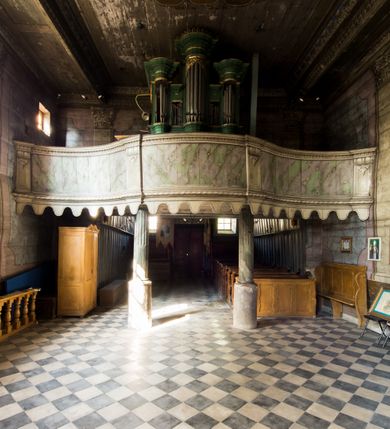 Zdjęcie nr 9: Kościół stanowi orientowaną, drewnianą świątynie wzniesioną na zrąb w układzie salowym z nawą na rzucie zbliżonym do kwadratu. Od wschody do nawy przylega węższe, prostokątne prezbiterium zamknięte trójbocznie. Od północy do prezbiterium dostawiono drewnianą zakrystię połączoną za pomocą portalu z prezbiterium kościoła. Do nawy od zachodu dostawiono czworoboczną wieżę o pochyłych ścianach, wzniesioną w konstrukcji słupowej. Wieńczy ją nadwieszona, czworoboczna izbica z ostrosłupowym, gontowym hełmem z krzyżem. W przyziemiach wieży urządzono kruchtę połączoną z nawą świątyni. Od północy, wschodu i południa kościół otaczają otwarte soboty, szalowane przy wieży. Elewacje zewnętrze zostały oszalowane lub też pokryte gontem. W nawie i prezbiterium przepruto okna parzyste, czworoboczne. Całość nakrywa dach gontowy o jednej kalenicy. Nad nawą w części wschodniej nadwieszono wieloboczną sygnaturkę w formie latarni z baniastym hełmem. Wnętrze nakryto stropami, dodatków w nawie z zaskrzynieniami. Pomiędzy prezbiterium, a nawą rozpięta jest ostrołukowa tęcza z fazowaną belką zawieszoną na kroksztynach z ustawionym na osi krucyfiksem. W zachodniej części nawy urządzono chór muzyczny o drewnianym, pełnym parapecie wklęsło-wypukłym z lambrekinem, wspartym na dwóch żłobkowanych kolumnach. Odrzwia południowe prowadzące do nawy ujęto w portal wycięty w ośli grzbiet. W prezbiterium ustawiono ołtarz główny, a w nawie dwa ołtarze boczne. 