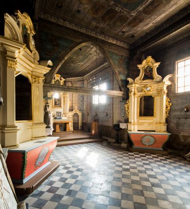 Zdjęcie nr 6: Kościół stanowi orientowaną, drewnianą świątynie wzniesioną na zrąb w układzie salowym z nawą na rzucie zbliżonym do kwadratu. Od wschody do nawy przylega węższe, prostokątne prezbiterium zamknięte trójbocznie. Od północy do prezbiterium dostawiono drewnianą zakrystię połączoną za pomocą portalu z prezbiterium kościoła. Do nawy od zachodu dostawiono czworoboczną wieżę o pochyłych ścianach, wzniesioną w konstrukcji słupowej. Wieńczy ją nadwieszona, czworoboczna izbica z ostrosłupowym, gontowym hełmem z krzyżem. W przyziemiach wieży urządzono kruchtę połączoną z nawą świątyni. Od północy, wschodu i południa kościół otaczają otwarte soboty, szalowane przy wieży. Elewacje zewnętrze zostały oszalowane lub też pokryte gontem. W nawie i prezbiterium przepruto okna parzyste, czworoboczne. Całość nakrywa dach gontowy o jednej kalenicy. Nad nawą w części wschodniej nadwieszono wieloboczną sygnaturkę w formie latarni z baniastym hełmem. Wnętrze nakryto stropami, dodatków w nawie z zaskrzynieniami. Pomiędzy prezbiterium, a nawą rozpięta jest ostrołukowa tęcza z fazowaną belką zawieszoną na kroksztynach z ustawionym na osi krucyfiksem. W zachodniej części nawy urządzono chór muzyczny o drewnianym, pełnym parapecie wklęsło-wypukłym z lambrekinem, wspartym na dwóch żłobkowanych kolumnach. Odrzwia południowe prowadzące do nawy ujęto w portal wycięty w ośli grzbiet. W prezbiterium ustawiono ołtarz główny, a w nawie dwa ołtarze boczne. 