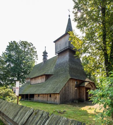 Zdjęcie nr 1: Kościół stanowi orientowaną, drewnianą świątynie wzniesioną na zrąb w układzie salowym z nawą na rzucie zbliżonym do kwadratu. Od wschody do nawy przylega węższe, prostokątne prezbiterium zamknięte trójbocznie. Od północy do prezbiterium dostawiono drewnianą zakrystię połączoną za pomocą portalu z prezbiterium kościoła. Do nawy od zachodu dostawiono czworoboczną wieżę o pochyłych ścianach, wzniesioną w konstrukcji słupowej. Wieńczy ją nadwieszona, czworoboczna izbica z ostrosłupowym, gontowym hełmem z krzyżem. W przyziemiach wieży urządzono kruchtę połączoną z nawą świątyni. Od północy, wschodu i południa kościół otaczają otwarte soboty, szalowane przy wieży. Elewacje zewnętrze zostały oszalowane lub też pokryte gontem. W nawie i prezbiterium przepruto okna parzyste, czworoboczne. Całość nakrywa dach gontowy o jednej kalenicy. Nad nawą w części wschodniej nadwieszono wieloboczną sygnaturkę w formie latarni z baniastym hełmem. Wnętrze nakryto stropami, dodatków w nawie z zaskrzynieniami. Pomiędzy prezbiterium, a nawą rozpięta jest ostrołukowa tęcza z fazowaną belką zawieszoną na kroksztynach z ustawionym na osi krucyfiksem. W zachodniej części nawy urządzono chór muzyczny o drewnianym, pełnym parapecie wklęsło-wypukłym z lambrekinem, wspartym na dwóch żłobkowanych kolumnach. Odrzwia południowe prowadzące do nawy ujęto w portal wycięty w ośli grzbiet. W prezbiterium ustawiono ołtarz główny, a w nawie dwa ołtarze boczne. 