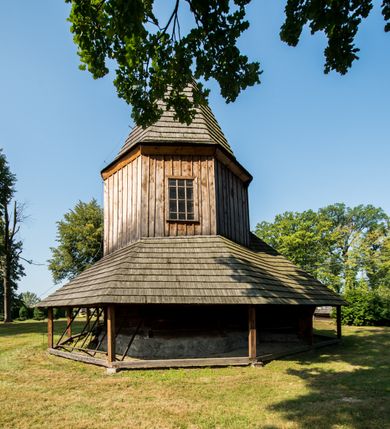Zdjęcie nr 13: Kościół stanowi orientowaną, drewnianą świątynie wzniesioną na zrąb w układzie salowym z nawą na rzucie zbliżonym do kwadratu. Od wschody do nawy przylega węższe, prostokątne prezbiterium zamknięte trójbocznie. Od północy do prezbiterium dostawiono drewnianą zakrystię połączoną za pomocą portalu z prezbiterium kościoła. Do nawy od zachodu dostawiono czworoboczną wieżę o pochyłych ścianach, wzniesioną w konstrukcji słupowej. Wieńczy ją nadwieszona, czworoboczna izbica z ostrosłupowym, gontowym hełmem z krzyżem. W przyziemiach wieży urządzono kruchtę połączoną z nawą świątyni. Od północy, wschodu i południa kościół otaczają otwarte soboty, szalowane przy wieży. Elewacje zewnętrze zostały oszalowane lub też pokryte gontem. W nawie i prezbiterium przepruto okna parzyste, czworoboczne. Całość nakrywa dach gontowy o jednej kalenicy. Nad nawą w części wschodniej nadwieszono wieloboczną sygnaturkę w formie latarni z baniastym hełmem. Wnętrze nakryto stropami, dodatków w nawie z zaskrzynieniami. Pomiędzy prezbiterium, a nawą rozpięta jest ostrołukowa tęcza z fazowaną belką zawieszoną na kroksztynach z ustawionym na osi krucyfiksem. W zachodniej części nawy urządzono chór muzyczny o drewnianym, pełnym parapecie wklęsło-wypukłym z lambrekinem, wspartym na dwóch żłobkowanych kolumnach. Odrzwia południowe prowadzące do nawy ujęto w portal wycięty w ośli grzbiet. W prezbiterium ustawiono ołtarz główny, a w nawie dwa ołtarze boczne. 