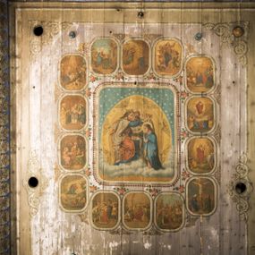 Zdjęcie nr 1: Dekoracją malarską pokryto fasety, stropy w nawie i prezbiterium, a także ich ściany oraz przestrzeń przedsionka pod wieżą. Ściany prezbiterium, nawy i przedsionka artykułowano za pomocą malowanych pilastrów o korynckich głowicach ustawionych na wysokich postumentach, podtrzymujących belkowanie. Pomiędzy pilastrami wprowadzono malowane czworoboczne płyciny o wklęsłych narożach z polem pokrytym marmoryzacją. Wąską fasetę podstropową ozdobiono fryzem z rytmicznie powtarzającym się motywem liścia palmetowego. Strop w prezbiterium i nawie uzyskał architektoniczne obramienie sceny centralnej ujętej w prostokątne pole o zaokrąglonych narożach, utworzone z iluzjonistycznie malowanych listew i zawieszonych pomiędzy nimi girland liściastych. W prezbiterium wyobrażono Trójcę Świętą, a w nawie Koronację Marii obwiedzioną tajemnicami różańcowymi w medalionach. Trójcę Świętą ukazano na obłokach na niebieskim tle. Majestatyczny Bóg Ojciec został ukazany w trzech czwartych w lewo jako siwobrody starzec o bujnych siwych włosach. W prawej ręce trzyma złote berło, lewą zaś odsuwa do siebie. Bóg Ojciec stopy wspiera o niebieski glob wyłaniający się z obłoków poniżej. Jego twarz charakteryzuje jasna karnacja, szeroko otwarte oczy, wydatny nos i usta. Głowę otacza długa, siwa broda i podobne włosy. Ubrany jest w mocno drapowaną białą tunikę i narzucony na nią rozwiany, złocisty płaszcz obszyty dekoracyjną bortą, spięty klamrą na lewym ramieniu. Obok Boga Ojca z lewej strony siedzi Chrystus, który obie, skrzyżowane nogi wspiera na globie. Zbawiciel prawą ręką podtrzymuje oparty o ramię drewniany krzyż, lewą zaś ma odsuniętą od siebie z gestem wskazującym na Ojca. Jezus został przedstawiony w trzech czwartych w prawo. Jest to dojrzały mężczyzna o pociągłej twarzy okolonej brązowymi, długimi włosami spływającymi na ramiona oraz brodą. Ma jasną karnację, prosty nos i wydatne usta. Nagi tors okrywa bladoszkarłatny płaszcz odsłaniający obie stopy Na dłoniach i stopach widoczne są rany po gwoździach. Głowę Jezusa okala świetlisty nimb. Powyżej obu postaci na tle rozjaśnionego nieba unosi się gołębica Ducha Świętego w promienistym otoku. Koronację Marii otoczoną przez owalne  medaliony ze scenami różańcowymi namalowano w polu dekoracyjnego, wydłużonego czworobocznego panneau o narożach utworzonych z roślinnego ornamentu powtórzonego symetrycznie na dłuższych bokach w środku. W centrum czworoboku o zaokrąglonych narożach obwiedzionych motywem różańca przedstawiono klęczącą na obłokach Marię przed koronującą ją Trójcą Świętą. Madonna jako młoda dziewczyna ujęta została w profilu w lewo. Lewą rękę ma przyłożoną do piersi, prawą zaś podaje synowi. Jej owalna twarz ma jasną karnację o wydatnym nosie i ustach. Głowę otaczają brązowe włosy spływające na plecy. Maria ubrana jest w lamowany złotą taśmą niebieski połaszcz oraz fragmentarycznie widoczną czerwoną suknię. Przed nią siedzi Chrystus, a za nim Bóg Ojciec. Pomiędzy nimi widać w jasnym otoku gołębicę Ducha Świętego. Jezus został ujęty w profilu w prawo. Prawą ręką unosi wraz Ojcem złotą koronę nad głową matki. Lewą zaś wspartą na kolanie trzyma jej prawą dłoń. Chrystus ma pociągłą twarz o jasnej karnacji i rumianych policzkach, wydatny nos i usta. Jego głowę otaczają długie brązowe włosy spływające na plecy oraz krótki zarost. Na głowie ma złoty diadem. Ubrany jest w niebieską tunikę i czerwony, mocno wywinięty płaszcz o jasnobeżowej podszewce. Spod tuniki widać fragmenty bosych stóp wspartych na obłokach. Obok Zbawiciela fragmentarycznie widać postać Boga Ojca ujętego frontalnie. Jest to starszy mężczyzna o siwym, obfitym zaroście i włosach. Ma wydatny nos i usta, a na głowie złoty diadem w formie mitry. Postacie ujmuje złocista, migdałowa mandorla utworzona z jasnego obramienia, na którym ukazano uskrzydlone główki serafinów. Dolną część mandorli spowijają obłoki. Całość ukazano na niebieskim tle usianym gwiazdami. Wokół centralnego przedstawienia rozmieszczono czternaście owalnych medalionów różańcowych. Ich narracja rozpoczyna się na osi ponad sceną z koronacją Marii. Idąc w lewo namalowano: Zwiastowanie Marii, Nawiedzenie św. Elżbiety, Boże Narodzenie, Ofiarowanie w świątyni, Znalezienie w świątyni, Modlitwa w Ogrójcu, Biczowanie, Cierniem ukoronowanie, Niesienie krzyża, Ukrzyżowanie, Zmartwychwstanie, Wniebowstąpienie, Zesłanie Ducha Świętego i Wniebowzięcie Marii. Pomiędzy medalionami namalowano czerwone róże.    