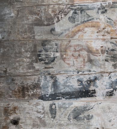 Zdjęcie nr 17: Dekoracją malarską pokryto fasety, stropy w nawie i prezbiterium, a także ich ściany oraz przestrzeń przedsionka pod wieżą. Ściany prezbiterium, nawy i przedsionka artykułowano za pomocą malowanych pilastrów o korynckich głowicach ustawionych na wysokich postumentach, podtrzymujących belkowanie. Pomiędzy pilastrami wprowadzono malowane czworoboczne płyciny o wklęsłych narożach z polem pokrytym marmoryzacją. Wąską fasetę podstropową ozdobiono fryzem z rytmicznie powtarzającym się motywem liścia palmetowego. Strop w prezbiterium i nawie uzyskał architektoniczne obramienie sceny centralnej ujętej w prostokątne pole o zaokrąglonych narożach, utworzone z iluzjonistycznie malowanych listew i zawieszonych pomiędzy nimi girland liściastych. W prezbiterium wyobrażono Trójcę Świętą, a w nawie Koronację Marii obwiedzioną tajemnicami różańcowymi w medalionach. Trójcę Świętą ukazano na obłokach na niebieskim tle. Majestatyczny Bóg Ojciec został ukazany w trzech czwartych w lewo jako siwobrody starzec o bujnych siwych włosach. W prawej ręce trzyma złote berło, lewą zaś odsuwa do siebie. Bóg Ojciec stopy wspiera o niebieski glob wyłaniający się z obłoków poniżej. Jego twarz charakteryzuje jasna karnacja, szeroko otwarte oczy, wydatny nos i usta. Głowę otacza długa, siwa broda i podobne włosy. Ubrany jest w mocno drapowaną białą tunikę i narzucony na nią rozwiany, złocisty płaszcz obszyty dekoracyjną bortą, spięty klamrą na lewym ramieniu. Obok Boga Ojca z lewej strony siedzi Chrystus, który obie, skrzyżowane nogi wspiera na globie. Zbawiciel prawą ręką podtrzymuje oparty o ramię drewniany krzyż, lewą zaś ma odsuniętą od siebie z gestem wskazującym na Ojca. Jezus został przedstawiony w trzech czwartych w prawo. Jest to dojrzały mężczyzna o pociągłej twarzy okolonej brązowymi, długimi włosami spływającymi na ramiona oraz brodą. Ma jasną karnację, prosty nos i wydatne usta. Nagi tors okrywa bladoszkarłatny płaszcz odsłaniający obie stopy Na dłoniach i stopach widoczne są rany po gwoździach. Głowę Jezusa okala świetlisty nimb. Powyżej obu postaci na tle rozjaśnionego nieba unosi się gołębica Ducha Świętego w promienistym otoku. Koronację Marii otoczoną przez owalne  medaliony ze scenami różańcowymi namalowano w polu dekoracyjnego, wydłużonego czworobocznego panneau o narożach utworzonych z roślinnego ornamentu powtórzonego symetrycznie na dłuższych bokach w środku. W centrum czworoboku o zaokrąglonych narożach obwiedzionych motywem różańca przedstawiono klęczącą na obłokach Marię przed koronującą ją Trójcą Świętą. Madonna jako młoda dziewczyna ujęta została w profilu w lewo. Lewą rękę ma przyłożoną do piersi, prawą zaś podaje synowi. Jej owalna twarz ma jasną karnację o wydatnym nosie i ustach. Głowę otaczają brązowe włosy spływające na plecy. Maria ubrana jest w lamowany złotą taśmą niebieski połaszcz oraz fragmentarycznie widoczną czerwoną suknię. Przed nią siedzi Chrystus, a za nim Bóg Ojciec. Pomiędzy nimi widać w jasnym otoku gołębicę Ducha Świętego. Jezus został ujęty w profilu w prawo. Prawą ręką unosi wraz Ojcem złotą koronę nad głową matki. Lewą zaś wspartą na kolanie trzyma jej prawą dłoń. Chrystus ma pociągłą twarz o jasnej karnacji i rumianych policzkach, wydatny nos i usta. Jego głowę otaczają długie brązowe włosy spływające na plecy oraz krótki zarost. Na głowie ma złoty diadem. Ubrany jest w niebieską tunikę i czerwony, mocno wywinięty płaszcz o jasnobeżowej podszewce. Spod tuniki widać fragmenty bosych stóp wspartych na obłokach. Obok Zbawiciela fragmentarycznie widać postać Boga Ojca ujętego frontalnie. Jest to starszy mężczyzna o siwym, obfitym zaroście i włosach. Ma wydatny nos i usta, a na głowie złoty diadem w formie mitry. Postacie ujmuje złocista, migdałowa mandorla utworzona z jasnego obramienia, na którym ukazano uskrzydlone główki serafinów. Dolną część mandorli spowijają obłoki. Całość ukazano na niebieskim tle usianym gwiazdami. Wokół centralnego przedstawienia rozmieszczono czternaście owalnych medalionów różańcowych. Ich narracja rozpoczyna się na osi ponad sceną z koronacją Marii. Idąc w lewo namalowano: Zwiastowanie Marii, Nawiedzenie św. Elżbiety, Boże Narodzenie, Ofiarowanie w świątyni, Znalezienie w świątyni, Modlitwa w Ogrójcu, Biczowanie, Cierniem ukoronowanie, Niesienie krzyża, Ukrzyżowanie, Zmartwychwstanie, Wniebowstąpienie, Zesłanie Ducha Świętego i Wniebowzięcie Marii. Pomiędzy medalionami namalowano czerwone róże.    