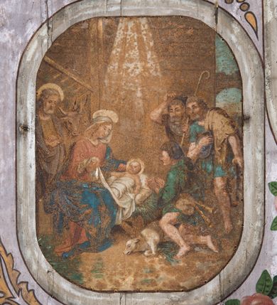 Zdjęcie nr 7: Dekoracją malarską pokryto fasety, stropy w nawie i prezbiterium, a także ich ściany oraz przestrzeń przedsionka pod wieżą. Ściany prezbiterium, nawy i przedsionka artykułowano za pomocą malowanych pilastrów o korynckich głowicach ustawionych na wysokich postumentach, podtrzymujących belkowanie. Pomiędzy pilastrami wprowadzono malowane czworoboczne płyciny o wklęsłych narożach z polem pokrytym marmoryzacją. Wąską fasetę podstropową ozdobiono fryzem z rytmicznie powtarzającym się motywem liścia palmetowego. Strop w prezbiterium i nawie uzyskał architektoniczne obramienie sceny centralnej ujętej w prostokątne pole o zaokrąglonych narożach, utworzone z iluzjonistycznie malowanych listew i zawieszonych pomiędzy nimi girland liściastych. W prezbiterium wyobrażono Trójcę Świętą, a w nawie Koronację Marii obwiedzioną tajemnicami różańcowymi w medalionach. Trójcę Świętą ukazano na obłokach na niebieskim tle. Majestatyczny Bóg Ojciec został ukazany w trzech czwartych w lewo jako siwobrody starzec o bujnych siwych włosach. W prawej ręce trzyma złote berło, lewą zaś odsuwa do siebie. Bóg Ojciec stopy wspiera o niebieski glob wyłaniający się z obłoków poniżej. Jego twarz charakteryzuje jasna karnacja, szeroko otwarte oczy, wydatny nos i usta. Głowę otacza długa, siwa broda i podobne włosy. Ubrany jest w mocno drapowaną białą tunikę i narzucony na nią rozwiany, złocisty płaszcz obszyty dekoracyjną bortą, spięty klamrą na lewym ramieniu. Obok Boga Ojca z lewej strony siedzi Chrystus, który obie, skrzyżowane nogi wspiera na globie. Zbawiciel prawą ręką podtrzymuje oparty o ramię drewniany krzyż, lewą zaś ma odsuniętą od siebie z gestem wskazującym na Ojca. Jezus został przedstawiony w trzech czwartych w prawo. Jest to dojrzały mężczyzna o pociągłej twarzy okolonej brązowymi, długimi włosami spływającymi na ramiona oraz brodą. Ma jasną karnację, prosty nos i wydatne usta. Nagi tors okrywa bladoszkarłatny płaszcz odsłaniający obie stopy Na dłoniach i stopach widoczne są rany po gwoździach. Głowę Jezusa okala świetlisty nimb. Powyżej obu postaci na tle rozjaśnionego nieba unosi się gołębica Ducha Świętego w promienistym otoku. Koronację Marii otoczoną przez owalne  medaliony ze scenami różańcowymi namalowano w polu dekoracyjnego, wydłużonego czworobocznego panneau o narożach utworzonych z roślinnego ornamentu powtórzonego symetrycznie na dłuższych bokach w środku. W centrum czworoboku o zaokrąglonych narożach obwiedzionych motywem różańca przedstawiono klęczącą na obłokach Marię przed koronującą ją Trójcą Świętą. Madonna jako młoda dziewczyna ujęta została w profilu w lewo. Lewą rękę ma przyłożoną do piersi, prawą zaś podaje synowi. Jej owalna twarz ma jasną karnację o wydatnym nosie i ustach. Głowę otaczają brązowe włosy spływające na plecy. Maria ubrana jest w lamowany złotą taśmą niebieski połaszcz oraz fragmentarycznie widoczną czerwoną suknię. Przed nią siedzi Chrystus, a za nim Bóg Ojciec. Pomiędzy nimi widać w jasnym otoku gołębicę Ducha Świętego. Jezus został ujęty w profilu w prawo. Prawą ręką unosi wraz Ojcem złotą koronę nad głową matki. Lewą zaś wspartą na kolanie trzyma jej prawą dłoń. Chrystus ma pociągłą twarz o jasnej karnacji i rumianych policzkach, wydatny nos i usta. Jego głowę otaczają długie brązowe włosy spływające na plecy oraz krótki zarost. Na głowie ma złoty diadem. Ubrany jest w niebieską tunikę i czerwony, mocno wywinięty płaszcz o jasnobeżowej podszewce. Spod tuniki widać fragmenty bosych stóp wspartych na obłokach. Obok Zbawiciela fragmentarycznie widać postać Boga Ojca ujętego frontalnie. Jest to starszy mężczyzna o siwym, obfitym zaroście i włosach. Ma wydatny nos i usta, a na głowie złoty diadem w formie mitry. Postacie ujmuje złocista, migdałowa mandorla utworzona z jasnego obramienia, na którym ukazano uskrzydlone główki serafinów. Dolną część mandorli spowijają obłoki. Całość ukazano na niebieskim tle usianym gwiazdami. Wokół centralnego przedstawienia rozmieszczono czternaście owalnych medalionów różańcowych. Ich narracja rozpoczyna się na osi ponad sceną z koronacją Marii. Idąc w lewo namalowano: Zwiastowanie Marii, Nawiedzenie św. Elżbiety, Boże Narodzenie, Ofiarowanie w świątyni, Znalezienie w świątyni, Modlitwa w Ogrójcu, Biczowanie, Cierniem ukoronowanie, Niesienie krzyża, Ukrzyżowanie, Zmartwychwstanie, Wniebowstąpienie, Zesłanie Ducha Świętego i Wniebowzięcie Marii. Pomiędzy medalionami namalowano czerwone róże.    