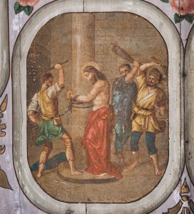 Zdjęcie nr 11: Dekoracją malarską pokryto fasety, stropy w nawie i prezbiterium, a także ich ściany oraz przestrzeń przedsionka pod wieżą. Ściany prezbiterium, nawy i przedsionka artykułowano za pomocą malowanych pilastrów o korynckich głowicach ustawionych na wysokich postumentach, podtrzymujących belkowanie. Pomiędzy pilastrami wprowadzono malowane czworoboczne płyciny o wklęsłych narożach z polem pokrytym marmoryzacją. Wąską fasetę podstropową ozdobiono fryzem z rytmicznie powtarzającym się motywem liścia palmetowego. Strop w prezbiterium i nawie uzyskał architektoniczne obramienie sceny centralnej ujętej w prostokątne pole o zaokrąglonych narożach, utworzone z iluzjonistycznie malowanych listew i zawieszonych pomiędzy nimi girland liściastych. W prezbiterium wyobrażono Trójcę Świętą, a w nawie Koronację Marii obwiedzioną tajemnicami różańcowymi w medalionach. Trójcę Świętą ukazano na obłokach na niebieskim tle. Majestatyczny Bóg Ojciec został ukazany w trzech czwartych w lewo jako siwobrody starzec o bujnych siwych włosach. W prawej ręce trzyma złote berło, lewą zaś odsuwa do siebie. Bóg Ojciec stopy wspiera o niebieski glob wyłaniający się z obłoków poniżej. Jego twarz charakteryzuje jasna karnacja, szeroko otwarte oczy, wydatny nos i usta. Głowę otacza długa, siwa broda i podobne włosy. Ubrany jest w mocno drapowaną białą tunikę i narzucony na nią rozwiany, złocisty płaszcz obszyty dekoracyjną bortą, spięty klamrą na lewym ramieniu. Obok Boga Ojca z lewej strony siedzi Chrystus, który obie, skrzyżowane nogi wspiera na globie. Zbawiciel prawą ręką podtrzymuje oparty o ramię drewniany krzyż, lewą zaś ma odsuniętą od siebie z gestem wskazującym na Ojca. Jezus został przedstawiony w trzech czwartych w prawo. Jest to dojrzały mężczyzna o pociągłej twarzy okolonej brązowymi, długimi włosami spływającymi na ramiona oraz brodą. Ma jasną karnację, prosty nos i wydatne usta. Nagi tors okrywa bladoszkarłatny płaszcz odsłaniający obie stopy Na dłoniach i stopach widoczne są rany po gwoździach. Głowę Jezusa okala świetlisty nimb. Powyżej obu postaci na tle rozjaśnionego nieba unosi się gołębica Ducha Świętego w promienistym otoku. Koronację Marii otoczoną przez owalne  medaliony ze scenami różańcowymi namalowano w polu dekoracyjnego, wydłużonego czworobocznego panneau o narożach utworzonych z roślinnego ornamentu powtórzonego symetrycznie na dłuższych bokach w środku. W centrum czworoboku o zaokrąglonych narożach obwiedzionych motywem różańca przedstawiono klęczącą na obłokach Marię przed koronującą ją Trójcą Świętą. Madonna jako młoda dziewczyna ujęta została w profilu w lewo. Lewą rękę ma przyłożoną do piersi, prawą zaś podaje synowi. Jej owalna twarz ma jasną karnację o wydatnym nosie i ustach. Głowę otaczają brązowe włosy spływające na plecy. Maria ubrana jest w lamowany złotą taśmą niebieski połaszcz oraz fragmentarycznie widoczną czerwoną suknię. Przed nią siedzi Chrystus, a za nim Bóg Ojciec. Pomiędzy nimi widać w jasnym otoku gołębicę Ducha Świętego. Jezus został ujęty w profilu w prawo. Prawą ręką unosi wraz Ojcem złotą koronę nad głową matki. Lewą zaś wspartą na kolanie trzyma jej prawą dłoń. Chrystus ma pociągłą twarz o jasnej karnacji i rumianych policzkach, wydatny nos i usta. Jego głowę otaczają długie brązowe włosy spływające na plecy oraz krótki zarost. Na głowie ma złoty diadem. Ubrany jest w niebieską tunikę i czerwony, mocno wywinięty płaszcz o jasnobeżowej podszewce. Spod tuniki widać fragmenty bosych stóp wspartych na obłokach. Obok Zbawiciela fragmentarycznie widać postać Boga Ojca ujętego frontalnie. Jest to starszy mężczyzna o siwym, obfitym zaroście i włosach. Ma wydatny nos i usta, a na głowie złoty diadem w formie mitry. Postacie ujmuje złocista, migdałowa mandorla utworzona z jasnego obramienia, na którym ukazano uskrzydlone główki serafinów. Dolną część mandorli spowijają obłoki. Całość ukazano na niebieskim tle usianym gwiazdami. Wokół centralnego przedstawienia rozmieszczono czternaście owalnych medalionów różańcowych. Ich narracja rozpoczyna się na osi ponad sceną z koronacją Marii. Idąc w lewo namalowano: Zwiastowanie Marii, Nawiedzenie św. Elżbiety, Boże Narodzenie, Ofiarowanie w świątyni, Znalezienie w świątyni, Modlitwa w Ogrójcu, Biczowanie, Cierniem ukoronowanie, Niesienie krzyża, Ukrzyżowanie, Zmartwychwstanie, Wniebowstąpienie, Zesłanie Ducha Świętego i Wniebowzięcie Marii. Pomiędzy medalionami namalowano czerwone róże.    