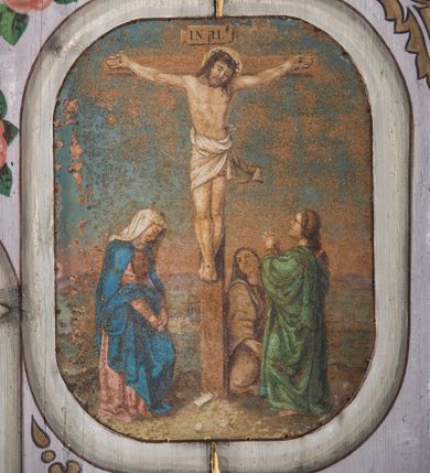 Zdjęcie nr 14: Dekoracją malarską pokryto fasety, stropy w nawie i prezbiterium, a także ich ściany oraz przestrzeń przedsionka pod wieżą. Ściany prezbiterium, nawy i przedsionka artykułowano za pomocą malowanych pilastrów o korynckich głowicach ustawionych na wysokich postumentach, podtrzymujących belkowanie. Pomiędzy pilastrami wprowadzono malowane czworoboczne płyciny o wklęsłych narożach z polem pokrytym marmoryzacją. Wąską fasetę podstropową ozdobiono fryzem z rytmicznie powtarzającym się motywem liścia palmetowego. Strop w prezbiterium i nawie uzyskał architektoniczne obramienie sceny centralnej ujętej w prostokątne pole o zaokrąglonych narożach, utworzone z iluzjonistycznie malowanych listew i zawieszonych pomiędzy nimi girland liściastych. W prezbiterium wyobrażono Trójcę Świętą, a w nawie Koronację Marii obwiedzioną tajemnicami różańcowymi w medalionach. Trójcę Świętą ukazano na obłokach na niebieskim tle. Majestatyczny Bóg Ojciec został ukazany w trzech czwartych w lewo jako siwobrody starzec o bujnych siwych włosach. W prawej ręce trzyma złote berło, lewą zaś odsuwa do siebie. Bóg Ojciec stopy wspiera o niebieski glob wyłaniający się z obłoków poniżej. Jego twarz charakteryzuje jasna karnacja, szeroko otwarte oczy, wydatny nos i usta. Głowę otacza długa, siwa broda i podobne włosy. Ubrany jest w mocno drapowaną białą tunikę i narzucony na nią rozwiany, złocisty płaszcz obszyty dekoracyjną bortą, spięty klamrą na lewym ramieniu. Obok Boga Ojca z lewej strony siedzi Chrystus, który obie, skrzyżowane nogi wspiera na globie. Zbawiciel prawą ręką podtrzymuje oparty o ramię drewniany krzyż, lewą zaś ma odsuniętą od siebie z gestem wskazującym na Ojca. Jezus został przedstawiony w trzech czwartych w prawo. Jest to dojrzały mężczyzna o pociągłej twarzy okolonej brązowymi, długimi włosami spływającymi na ramiona oraz brodą. Ma jasną karnację, prosty nos i wydatne usta. Nagi tors okrywa bladoszkarłatny płaszcz odsłaniający obie stopy Na dłoniach i stopach widoczne są rany po gwoździach. Głowę Jezusa okala świetlisty nimb. Powyżej obu postaci na tle rozjaśnionego nieba unosi się gołębica Ducha Świętego w promienistym otoku. Koronację Marii otoczoną przez owalne  medaliony ze scenami różańcowymi namalowano w polu dekoracyjnego, wydłużonego czworobocznego panneau o narożach utworzonych z roślinnego ornamentu powtórzonego symetrycznie na dłuższych bokach w środku. W centrum czworoboku o zaokrąglonych narożach obwiedzionych motywem różańca przedstawiono klęczącą na obłokach Marię przed koronującą ją Trójcą Świętą. Madonna jako młoda dziewczyna ujęta została w profilu w lewo. Lewą rękę ma przyłożoną do piersi, prawą zaś podaje synowi. Jej owalna twarz ma jasną karnację o wydatnym nosie i ustach. Głowę otaczają brązowe włosy spływające na plecy. Maria ubrana jest w lamowany złotą taśmą niebieski połaszcz oraz fragmentarycznie widoczną czerwoną suknię. Przed nią siedzi Chrystus, a za nim Bóg Ojciec. Pomiędzy nimi widać w jasnym otoku gołębicę Ducha Świętego. Jezus został ujęty w profilu w prawo. Prawą ręką unosi wraz Ojcem złotą koronę nad głową matki. Lewą zaś wspartą na kolanie trzyma jej prawą dłoń. Chrystus ma pociągłą twarz o jasnej karnacji i rumianych policzkach, wydatny nos i usta. Jego głowę otaczają długie brązowe włosy spływające na plecy oraz krótki zarost. Na głowie ma złoty diadem. Ubrany jest w niebieską tunikę i czerwony, mocno wywinięty płaszcz o jasnobeżowej podszewce. Spod tuniki widać fragmenty bosych stóp wspartych na obłokach. Obok Zbawiciela fragmentarycznie widać postać Boga Ojca ujętego frontalnie. Jest to starszy mężczyzna o siwym, obfitym zaroście i włosach. Ma wydatny nos i usta, a na głowie złoty diadem w formie mitry. Postacie ujmuje złocista, migdałowa mandorla utworzona z jasnego obramienia, na którym ukazano uskrzydlone główki serafinów. Dolną część mandorli spowijają obłoki. Całość ukazano na niebieskim tle usianym gwiazdami. Wokół centralnego przedstawienia rozmieszczono czternaście owalnych medalionów różańcowych. Ich narracja rozpoczyna się na osi ponad sceną z koronacją Marii. Idąc w lewo namalowano: Zwiastowanie Marii, Nawiedzenie św. Elżbiety, Boże Narodzenie, Ofiarowanie w świątyni, Znalezienie w świątyni, Modlitwa w Ogrójcu, Biczowanie, Cierniem ukoronowanie, Niesienie krzyża, Ukrzyżowanie, Zmartwychwstanie, Wniebowstąpienie, Zesłanie Ducha Świętego i Wniebowzięcie Marii. Pomiędzy medalionami namalowano czerwone róże.    