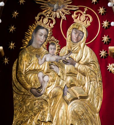 Zdjęcie nr 3: Trójosiowy ołtarz przyścienny uzyskał formę architektonicznej nastawy jednokondygnacyjnej ze zwieńczeniem. Sarkofagowy stipes ołtarzowy wsparto na profilowanym cokole, wieńcząc go gzymsem. Wspiera on drewnianą mensę z portatylem. Ołtarz ustawiono na podeście z dwoma gradusami. Retabulum zostało zaopatrzone w wysoki, drewniany cokół zwieńczony dekoracyjną listwą z motywami roślinno-kwiatowymi. Na cokole ustawiono trójosiową predellę. Jej środkową część wydzielono za pomocą wysokich, fazowanych postumentów, pomiędzy którymi znalazła się płycina z połączonymi ze sobą dwiema arkadami, których łuki przechodzą na profilowany wspornik ozdobiony ornamentem roślinno-kwiatowym. Płaskorzeźbiony ornament roślinno-kwiatowy poprowadzono także w świetle arkady. Po bokach widoczne są dwie kolejne, półkoliste arkady z podłuczami wypełnionymi arkaturą o czerwonych polach z płaskorzeźbionym ornamentem kwiatowo-roślinnym. W kondygnacji na osi środkowej usytuowano półkolistą arkadę ze zdwojonymi archiwoltami, wspartymi na podwójnych półkolumnach, o prostych bazach i kapitelach z motywem roślinnym. Arkadę flankują postumenty z półkoliście zamkniętymi płycinami o zielonych polach, wypełnionych płaskorzeźbionymi, skrzydlatymi główkami aniołków i motywami roślinnymi. Ponad gzymsem znalazły się półkoliste muszle. Arkadę zdobi biegnący po zewnętrznej ornament utworzony ze stylizowanych liści oraz szyszek, przedzielony na osi krzyżem. We wnętrz arkady umieszczono obraz w kształcie prostokąta zakończony półkoliście z przedstawieniem św. Anny Samotrzeć, dekorowany sukienką wotywną, nałożoną na aksamitne tło. Obraz zasłaniają dwie zasuwy z przedstawieniem Matki Boskiej Nieustającej Pomocy i św. Józefa. Poniżej obrazu widoczny jest parapet cokołu wprowadzonego w dolnej części arkady. Arkadę wieńczy belkowanie wyłamane na osi w formie nadwieszonego trójkąta, wsparte na dwóch  postumentach. Szczyt dekoruje ornament roślinny z motywem kół oraz ćwierci półkolistych muszli i stylizowany neogotycki kwiaton. Postumenty, wypełnione zaślepionym maswerkiem, ponad gzymsem przechodzą w dwie czworoboczne fiale, zakończone ostrosłupowym zwieńczeniem dekorowanym żabkami i kwiatonami, przechodzącymi w krzyże o trójlistnie zakończonych ramionach. W dolnych częściach fial usytuowano wycinane, trójlistne, zielone płyciny z motywem koniczyny przechodzące w listewki zakończone trójlistnie. Pomiędzy fialami wypiętrzono zwieńczenie utworzone z ostrołukowej arkady wspartej na zdwojonych półkolumnach. Na szczycie arkady umieszczono stylizowany neogotycki kwiaton, a po bokach płaskorzeźbione ornamenty kwiatowo-roślinne. Pod arkadą w polu zwieńczenia umieszczono prostokątny obraz zamknięty półkoliście z przedstawieniem Archanioła Rafała i Tobiasza. W osiach bocznych retabulum na poziomie kondygnacji znalazły się dwie wnęki arkadowe wsparte na kolumnach o roślinnych kapitelach i prostych bazach, umieszczonych na niskich cokołach. Całość została wsparta na cokoliku dekorowanym ornamentem roślinnym. Półkoliste arkady wypełniono pseudogotyckim maswerkiem. We wnękach ustawiono pełnoplastyczne rzeźby św. Zachariasza i św. Elżbiety. Powyżej usytuowano dekoracyjne zwieńczenie nawiązujące do pseudogotyckich fial z trzema sterczynami.