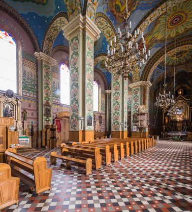 Zdjęcie nr 16: Orientowany kościół pw. Wszystkich Świętych w Wieprzu został wzniesiony w układzie trójnawowej hali z prostokątnym prezbiterium zamkniętym płaską apsydą na przedłużeniu nawy głównej, flankowanego od południa kaplicą, a od północy piętrową zakrystią. Od zachodu do trójprzęsłowego korpusu nawowego dostawiono nieznacznie wysuniętą do przodu czworoboczną wieżę, flankowaną po bokach dwoma aneksami tej samej wysokości, co nawa i aneksy przy prezbiterium. Całość nakryto miedzianym dachem siodłowym. Przy końcu nawy od wschodu na dachu nadwieszono sygnaturkę w formie latarni zwieńczonej ostrosłupowym hełmem. Elewacje zewnętrzne przeprute półokrągłymi oknami artykułowano za pomocą pilastrów o prostych głowicach wspartych na wysoki cokołach połączonych ze sobą gzymsem, podtrzymujących fazowane belkowanie przechodzące w profilowany gzyms koronujący. Elewacje wieży podzielona na dwie strefy rozdzielone belkowaniem wyłamanym w partii masywu wieżowego. W dolnej strefie w przyziemiu urządzono kruchtę, do której wejście na osi flankowane jest masywnym portalem utworzonym z dwóch czworobocznych podpór wspierających trójkątny przyczółek, ponad którym przepruto półokrągłe okno. Ponad gzymsem, w górnej strefie, zastosowano podział ramowy, ujmujący okulus, który pełni partię cokołową wspierającą flankujące górną część wieży pary pilastrów na każdej z czterech elewacji. Pilastry ustawione na postumentach o gładkich trzonach i kompozytowych głowicach wspierają fazowane belkowanie przechodzące w gzyms koronujący. Pomiędzy pilastrami przepruto półokrągłe okna z umieszczonymi nad nimi trójkątnymi przyczółkami. Gzyms został wyłamany na każdej z osi środkowej, tworząc miejsce dla tarcz zegarowych. Wieżę zwieńczono baniastym hełmem z czworoboczną latarnią nakrytą cebulastym zwieńczeniem z krzyżem. Nawa główna otwiera się do naw bocznych z każdej strony otwiera się do naw bocznych z każdej strony trzema opilastrowanymi arkadami filarowymi. Wnętrze nakryto sklepieniem krzyżowym. Chór muzyczny zajmuje szerokość całego korpusu nawowego, wspierając się na pięciu arkadach - trzy w nawie głównej i po jednej w nawach bocznych. Balustrada na chórze artykułowana jest płycinami rozdzielonymi niskim postumentami. W prezbiterium ustawiono ołtarz główny, a na zakończeniu naw ołtarze boczne. Dwa ołtarze boczne znalazły się także w części zachodniej nawy południowej i północnej.