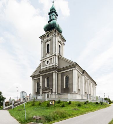 Zdjęcie nr 3: Orientowany kościół pw. Wszystkich Świętych w Wieprzu został wzniesiony w układzie trójnawowej hali z prostokątnym prezbiterium zamkniętym płaską apsydą na przedłużeniu nawy głównej, flankowanego od południa kaplicą, a od północy piętrową zakrystią. Od zachodu do trójprzęsłowego korpusu nawowego dostawiono nieznacznie wysuniętą do przodu czworoboczną wieżę, flankowaną po bokach dwoma aneksami tej samej wysokości, co nawa i aneksy przy prezbiterium. Całość nakryto miedzianym dachem siodłowym. Przy końcu nawy od wschodu na dachu nadwieszono sygnaturkę w formie latarni zwieńczonej ostrosłupowym hełmem. Elewacje zewnętrzne przeprute półokrągłymi oknami artykułowano za pomocą pilastrów o prostych głowicach wspartych na wysoki cokołach połączonych ze sobą gzymsem, podtrzymujących fazowane belkowanie przechodzące w profilowany gzyms koronujący. Elewacje wieży podzielona na dwie strefy rozdzielone belkowaniem wyłamanym w partii masywu wieżowego. W dolnej strefie w przyziemiu urządzono kruchtę, do której wejście na osi flankowane jest masywnym portalem utworzonym z dwóch czworobocznych podpór wspierających trójkątny przyczółek, ponad którym przepruto półokrągłe okno. Ponad gzymsem, w górnej strefie, zastosowano podział ramowy, ujmujący okulus, który pełni partię cokołową wspierającą flankujące górną część wieży pary pilastrów na każdej z czterech elewacji. Pilastry ustawione na postumentach o gładkich trzonach i kompozytowych głowicach wspierają fazowane belkowanie przechodzące w gzyms koronujący. Pomiędzy pilastrami przepruto półokrągłe okna z umieszczonymi nad nimi trójkątnymi przyczółkami. Gzyms został wyłamany na każdej z osi środkowej, tworząc miejsce dla tarcz zegarowych. Wieżę zwieńczono baniastym hełmem z czworoboczną latarnią nakrytą cebulastym zwieńczeniem z krzyżem. Nawa główna otwiera się do naw bocznych z każdej strony otwiera się do naw bocznych z każdej strony trzema opilastrowanymi arkadami filarowymi. Wnętrze nakryto sklepieniem krzyżowym. Chór muzyczny zajmuje szerokość całego korpusu nawowego, wspierając się na pięciu arkadach - trzy w nawie głównej i po jednej w nawach bocznych. Balustrada na chórze artykułowana jest płycinami rozdzielonymi niskim postumentami. W prezbiterium ustawiono ołtarz główny, a na zakończeniu naw ołtarze boczne. Dwa ołtarze boczne znalazły się także w części zachodniej nawy południowej i północnej.