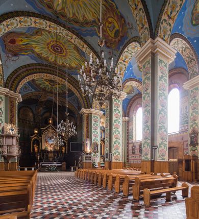 Zdjęcie nr 15: Orientowany kościół pw. Wszystkich Świętych w Wieprzu został wzniesiony w układzie trójnawowej hali z prostokątnym prezbiterium zamkniętym płaską apsydą na przedłużeniu nawy głównej, flankowanego od południa kaplicą, a od północy piętrową zakrystią. Od zachodu do trójprzęsłowego korpusu nawowego dostawiono nieznacznie wysuniętą do przodu czworoboczną wieżę, flankowaną po bokach dwoma aneksami tej samej wysokości, co nawa i aneksy przy prezbiterium. Całość nakryto miedzianym dachem siodłowym. Przy końcu nawy od wschodu na dachu nadwieszono sygnaturkę w formie latarni zwieńczonej ostrosłupowym hełmem. Elewacje zewnętrzne przeprute półokrągłymi oknami artykułowano za pomocą pilastrów o prostych głowicach wspartych na wysoki cokołach połączonych ze sobą gzymsem, podtrzymujących fazowane belkowanie przechodzące w profilowany gzyms koronujący. Elewacje wieży podzielona na dwie strefy rozdzielone belkowaniem wyłamanym w partii masywu wieżowego. W dolnej strefie w przyziemiu urządzono kruchtę, do której wejście na osi flankowane jest masywnym portalem utworzonym z dwóch czworobocznych podpór wspierających trójkątny przyczółek, ponad którym przepruto półokrągłe okno. Ponad gzymsem, w górnej strefie, zastosowano podział ramowy, ujmujący okulus, który pełni partię cokołową wspierającą flankujące górną część wieży pary pilastrów na każdej z czterech elewacji. Pilastry ustawione na postumentach o gładkich trzonach i kompozytowych głowicach wspierają fazowane belkowanie przechodzące w gzyms koronujący. Pomiędzy pilastrami przepruto półokrągłe okna z umieszczonymi nad nimi trójkątnymi przyczółkami. Gzyms został wyłamany na każdej z osi środkowej, tworząc miejsce dla tarcz zegarowych. Wieżę zwieńczono baniastym hełmem z czworoboczną latarnią nakrytą cebulastym zwieńczeniem z krzyżem. Nawa główna otwiera się do naw bocznych z każdej strony otwiera się do naw bocznych z każdej strony trzema opilastrowanymi arkadami filarowymi. Wnętrze nakryto sklepieniem krzyżowym. Chór muzyczny zajmuje szerokość całego korpusu nawowego, wspierając się na pięciu arkadach - trzy w nawie głównej i po jednej w nawach bocznych. Balustrada na chórze artykułowana jest płycinami rozdzielonymi niskim postumentami. W prezbiterium ustawiono ołtarz główny, a na zakończeniu naw ołtarze boczne. Dwa ołtarze boczne znalazły się także w części zachodniej nawy południowej i północnej.