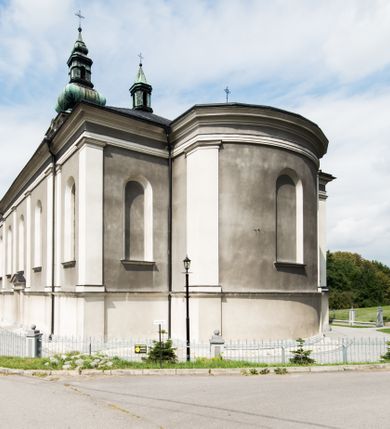 Zdjęcie nr 6: Orientowany kościół pw. Wszystkich Świętych w Wieprzu został wzniesiony w układzie trójnawowej hali z prostokątnym prezbiterium zamkniętym płaską apsydą na przedłużeniu nawy głównej, flankowanego od południa kaplicą, a od północy piętrową zakrystią. Od zachodu do trójprzęsłowego korpusu nawowego dostawiono nieznacznie wysuniętą do przodu czworoboczną wieżę, flankowaną po bokach dwoma aneksami tej samej wysokości, co nawa i aneksy przy prezbiterium. Całość nakryto miedzianym dachem siodłowym. Przy końcu nawy od wschodu na dachu nadwieszono sygnaturkę w formie latarni zwieńczonej ostrosłupowym hełmem. Elewacje zewnętrzne przeprute półokrągłymi oknami artykułowano za pomocą pilastrów o prostych głowicach wspartych na wysoki cokołach połączonych ze sobą gzymsem, podtrzymujących fazowane belkowanie przechodzące w profilowany gzyms koronujący. Elewacje wieży podzielona na dwie strefy rozdzielone belkowaniem wyłamanym w partii masywu wieżowego. W dolnej strefie w przyziemiu urządzono kruchtę, do której wejście na osi flankowane jest masywnym portalem utworzonym z dwóch czworobocznych podpór wspierających trójkątny przyczółek, ponad którym przepruto półokrągłe okno. Ponad gzymsem, w górnej strefie, zastosowano podział ramowy, ujmujący okulus, który pełni partię cokołową wspierającą flankujące górną część wieży pary pilastrów na każdej z czterech elewacji. Pilastry ustawione na postumentach o gładkich trzonach i kompozytowych głowicach wspierają fazowane belkowanie przechodzące w gzyms koronujący. Pomiędzy pilastrami przepruto półokrągłe okna z umieszczonymi nad nimi trójkątnymi przyczółkami. Gzyms został wyłamany na każdej z osi środkowej, tworząc miejsce dla tarcz zegarowych. Wieżę zwieńczono baniastym hełmem z czworoboczną latarnią nakrytą cebulastym zwieńczeniem z krzyżem. Nawa główna otwiera się do naw bocznych z każdej strony otwiera się do naw bocznych z każdej strony trzema opilastrowanymi arkadami filarowymi. Wnętrze nakryto sklepieniem krzyżowym. Chór muzyczny zajmuje szerokość całego korpusu nawowego, wspierając się na pięciu arkadach - trzy w nawie głównej i po jednej w nawach bocznych. Balustrada na chórze artykułowana jest płycinami rozdzielonymi niskim postumentami. W prezbiterium ustawiono ołtarz główny, a na zakończeniu naw ołtarze boczne. Dwa ołtarze boczne znalazły się także w części zachodniej nawy południowej i północnej.