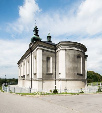 Zdjęcie nr 7: Orientowany kościół pw. Wszystkich Świętych w Wieprzu został wzniesiony w układzie trójnawowej hali z prostokątnym prezbiterium zamkniętym płaską apsydą na przedłużeniu nawy głównej, flankowanego od południa kaplicą, a od północy piętrową zakrystią. Od zachodu do trójprzęsłowego korpusu nawowego dostawiono nieznacznie wysuniętą do przodu czworoboczną wieżę, flankowaną po bokach dwoma aneksami tej samej wysokości, co nawa i aneksy przy prezbiterium. Całość nakryto miedzianym dachem siodłowym. Przy końcu nawy od wschodu na dachu nadwieszono sygnaturkę w formie latarni zwieńczonej ostrosłupowym hełmem. Elewacje zewnętrzne przeprute półokrągłymi oknami artykułowano za pomocą pilastrów o prostych głowicach wspartych na wysoki cokołach połączonych ze sobą gzymsem, podtrzymujących fazowane belkowanie przechodzące w profilowany gzyms koronujący. Elewacje wieży podzielona na dwie strefy rozdzielone belkowaniem wyłamanym w partii masywu wieżowego. W dolnej strefie w przyziemiu urządzono kruchtę, do której wejście na osi flankowane jest masywnym portalem utworzonym z dwóch czworobocznych podpór wspierających trójkątny przyczółek, ponad którym przepruto półokrągłe okno. Ponad gzymsem, w górnej strefie, zastosowano podział ramowy, ujmujący okulus, który pełni partię cokołową wspierającą flankujące górną część wieży pary pilastrów na każdej z czterech elewacji. Pilastry ustawione na postumentach o gładkich trzonach i kompozytowych głowicach wspierają fazowane belkowanie przechodzące w gzyms koronujący. Pomiędzy pilastrami przepruto półokrągłe okna z umieszczonymi nad nimi trójkątnymi przyczółkami. Gzyms został wyłamany na każdej z osi środkowej, tworząc miejsce dla tarcz zegarowych. Wieżę zwieńczono baniastym hełmem z czworoboczną latarnią nakrytą cebulastym zwieńczeniem z krzyżem. Nawa główna otwiera się do naw bocznych z każdej strony otwiera się do naw bocznych z każdej strony trzema opilastrowanymi arkadami filarowymi. Wnętrze nakryto sklepieniem krzyżowym. Chór muzyczny zajmuje szerokość całego korpusu nawowego, wspierając się na pięciu arkadach - trzy w nawie głównej i po jednej w nawach bocznych. Balustrada na chórze artykułowana jest płycinami rozdzielonymi niskim postumentami. W prezbiterium ustawiono ołtarz główny, a na zakończeniu naw ołtarze boczne. Dwa ołtarze boczne znalazły się także w części zachodniej nawy południowej i północnej.