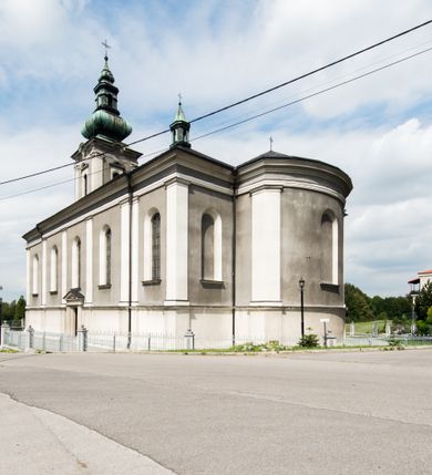 Zdjęcie nr 8: Orientowany kościół pw. Wszystkich Świętych w Wieprzu został wzniesiony w układzie trójnawowej hali z prostokątnym prezbiterium zamkniętym płaską apsydą na przedłużeniu nawy głównej, flankowanego od południa kaplicą, a od północy piętrową zakrystią. Od zachodu do trójprzęsłowego korpusu nawowego dostawiono nieznacznie wysuniętą do przodu czworoboczną wieżę, flankowaną po bokach dwoma aneksami tej samej wysokości, co nawa i aneksy przy prezbiterium. Całość nakryto miedzianym dachem siodłowym. Przy końcu nawy od wschodu na dachu nadwieszono sygnaturkę w formie latarni zwieńczonej ostrosłupowym hełmem. Elewacje zewnętrzne przeprute półokrągłymi oknami artykułowano za pomocą pilastrów o prostych głowicach wspartych na wysoki cokołach połączonych ze sobą gzymsem, podtrzymujących fazowane belkowanie przechodzące w profilowany gzyms koronujący. Elewacje wieży podzielona na dwie strefy rozdzielone belkowaniem wyłamanym w partii masywu wieżowego. W dolnej strefie w przyziemiu urządzono kruchtę, do której wejście na osi flankowane jest masywnym portalem utworzonym z dwóch czworobocznych podpór wspierających trójkątny przyczółek, ponad którym przepruto półokrągłe okno. Ponad gzymsem, w górnej strefie, zastosowano podział ramowy, ujmujący okulus, który pełni partię cokołową wspierającą flankujące górną część wieży pary pilastrów na każdej z czterech elewacji. Pilastry ustawione na postumentach o gładkich trzonach i kompozytowych głowicach wspierają fazowane belkowanie przechodzące w gzyms koronujący. Pomiędzy pilastrami przepruto półokrągłe okna z umieszczonymi nad nimi trójkątnymi przyczółkami. Gzyms został wyłamany na każdej z osi środkowej, tworząc miejsce dla tarcz zegarowych. Wieżę zwieńczono baniastym hełmem z czworoboczną latarnią nakrytą cebulastym zwieńczeniem z krzyżem. Nawa główna otwiera się do naw bocznych z każdej strony otwiera się do naw bocznych z każdej strony trzema opilastrowanymi arkadami filarowymi. Wnętrze nakryto sklepieniem krzyżowym. Chór muzyczny zajmuje szerokość całego korpusu nawowego, wspierając się na pięciu arkadach - trzy w nawie głównej i po jednej w nawach bocznych. Balustrada na chórze artykułowana jest płycinami rozdzielonymi niskim postumentami. W prezbiterium ustawiono ołtarz główny, a na zakończeniu naw ołtarze boczne. Dwa ołtarze boczne znalazły się także w części zachodniej nawy południowej i północnej.