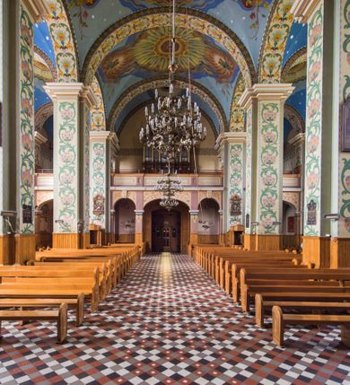 Zdjęcie nr 20: Orientowany kościół pw. Wszystkich Świętych w Wieprzu został wzniesiony w układzie trójnawowej hali z prostokątnym prezbiterium zamkniętym płaską apsydą na przedłużeniu nawy głównej, flankowanego od południa kaplicą, a od północy piętrową zakrystią. Od zachodu do trójprzęsłowego korpusu nawowego dostawiono nieznacznie wysuniętą do przodu czworoboczną wieżę, flankowaną po bokach dwoma aneksami tej samej wysokości, co nawa i aneksy przy prezbiterium. Całość nakryto miedzianym dachem siodłowym. Przy końcu nawy od wschodu na dachu nadwieszono sygnaturkę w formie latarni zwieńczonej ostrosłupowym hełmem. Elewacje zewnętrzne przeprute półokrągłymi oknami artykułowano za pomocą pilastrów o prostych głowicach wspartych na wysoki cokołach połączonych ze sobą gzymsem, podtrzymujących fazowane belkowanie przechodzące w profilowany gzyms koronujący. Elewacje wieży podzielona na dwie strefy rozdzielone belkowaniem wyłamanym w partii masywu wieżowego. W dolnej strefie w przyziemiu urządzono kruchtę, do której wejście na osi flankowane jest masywnym portalem utworzonym z dwóch czworobocznych podpór wspierających trójkątny przyczółek, ponad którym przepruto półokrągłe okno. Ponad gzymsem, w górnej strefie, zastosowano podział ramowy, ujmujący okulus, który pełni partię cokołową wspierającą flankujące górną część wieży pary pilastrów na każdej z czterech elewacji. Pilastry ustawione na postumentach o gładkich trzonach i kompozytowych głowicach wspierają fazowane belkowanie przechodzące w gzyms koronujący. Pomiędzy pilastrami przepruto półokrągłe okna z umieszczonymi nad nimi trójkątnymi przyczółkami. Gzyms został wyłamany na każdej z osi środkowej, tworząc miejsce dla tarcz zegarowych. Wieżę zwieńczono baniastym hełmem z czworoboczną latarnią nakrytą cebulastym zwieńczeniem z krzyżem. Nawa główna otwiera się do naw bocznych z każdej strony otwiera się do naw bocznych z każdej strony trzema opilastrowanymi arkadami filarowymi. Wnętrze nakryto sklepieniem krzyżowym. Chór muzyczny zajmuje szerokość całego korpusu nawowego, wspierając się na pięciu arkadach - trzy w nawie głównej i po jednej w nawach bocznych. Balustrada na chórze artykułowana jest płycinami rozdzielonymi niskim postumentami. W prezbiterium ustawiono ołtarz główny, a na zakończeniu naw ołtarze boczne. Dwa ołtarze boczne znalazły się także w części zachodniej nawy południowej i północnej.