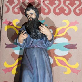 Zdjęcie nr 1: Rzeźba wyobraża frontalnie w całej postaci w kontrapoście św. Pawła Pustelnika. Mnich ma głowę ujętą w trzech czwartych w lewo, obie zaś ręce ma wyciągnięte przed sobą na wysokości piersi. Głowę świętego otacza długa, czarna broda oraz włosy. Ma pociągłą twarz o zapadniętych oczach, wydatny nos i usta. Ubrany jest w niebiesko-filoletową tunikę przewiązaną w pasie, spod której na dole widać fragmenty stóp.   