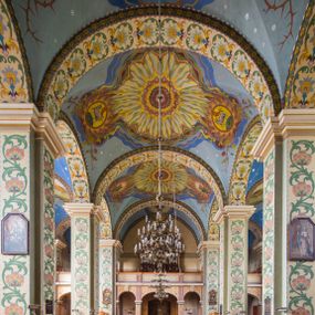 Zdjęcie nr 1: Dekoracja malarska wnętrza kościoła została oparta zasadniczo na motywach ornamentalnych, gdzie wyjątek stanowi monumentalna scena ukazująca uczniów idących do Emaus, usytuowana na północnej ścianie prezbiterium, nad wejściem do zakrystii. Wyobrażono tu w malowanym, ornamentalnym obramieniu scenę wpisaną w stojący prostokąt, zamknięty od góry łukiem półkolistym. W centrum kompozycji ukazano Chrystusa, którego zatrzymują stojący na schodach gospody dwaj uczniowie idący do Emaus. Stojący Zbawiciel został wyobrażony z lewej strony w trzech czwartych w prawo. Prawą ręką podtrzymuje połę płaszcza, lewa jest niewidoczna. Jest to dojrzały mężczyzna o pociągłej twarzy z wydatnym nosem i ustami, długimi włosami spływającymi na ramiona oraz brodą okalającą twarz o jasnej karnacji. Zbawiciel ubrany jest w białą tunikę i szkarłatny płaszcz. Do niego zwraca się jedne z uczniów ukazany tyłem do widza w trzech czwartych w lewo. Jest to dojrzały mężczyzna, który lewą rękę wyciąga w stronę Jezusa, prawą zaś zdaje się zapraszać do wejścia na schody. Jego twarz okolona krótkimi włosami z brodą i wydatnym nosem i ustami widoczna jest z profilu. Ubrany jest w jasną tunikę oraz jasnobeżowy płaszcz. Przed nim z prawej strony na stopniach wiodących do drzwi gospody stoi drugi uczeń. Ujęto go frontalnie w kontrapoście z głową w trzech czwartych w lewo. W prawej ręce trzyma laskę, lewą zaś wskazuje na drzwi zajazdu. Jest to młody mężczyzna o pociągłej twarzy i długich włosach spływających na plecy. Ubrany jest w przewiązaną w pasie tunikę oraz narzucony na ramiona bladoszkarłatny płaszcz. Za przedstawionymi postaciami widać fragment wschodniej architektury oraz rozbudowaną sekwencję pejzażową z elementem bramy miejskiej oraz roślinnością na tle wieczornego nieba. Poniżej przedstawienia umieszczono napis: &quot;Uczniowie z Emaus&quot; podpis: &quot;ZOSTAŃ Z NAMI, BOĆ SIĘ MA KU WIECZOROWI I DZIEŃ SIĘ JUŻ NACHYLIŁ - ŚW[IĘTY] ŁUKASZ XXIV&quot;. Bogactwo ornamentalnej dekoracji malarskiej zostało podporządkowane architekturze wnętrza. Partię ścian pokryto malaturą o charakterze dywanowym, ułożoną strefowo z powtarzających się rytmicznie kolorowych motywów ornamentalnych. Gurty sklepienne oraz trzony pilastrów na filarach międzynawowych pokryto wykonanymi na niebieskim lub błękitnym tle ornamentalnymi pasami z motywem fantazyjnych kwiatów i wici roślinnych. Partię sklepienne w kolejnych przęsłach w nawach udekorowano koncentrycznie rozchodzą się płomienistą i falującą ornamentyką, z wplecionymi motywami symbolu Najświętszego Serca Pana Jezusa, Apokaliptycznego Baranka, kielicha z hostią w otoczeniu kłosów zbóż i winnej latorośli, a także gałązek różanych i cierniowych. Na ścianach prezbiterium zastosowano podział strefowy. Dolne przestrzenie ozdobiono pasma ornamentalnymi. Powyżej rozmieszczono strefę z przedstawieniem rosnących obok siebie kwitów lilii. U samej góry sięgnięto do motywów rybich łusek oraz stylizowanej, wielobarwnej ornamentyki fantazyjnej. Gurty sklepienia udekorowano pasami opartymi na stylizowanych skrzydłach serafinów. Natomiast w poszczególnych polach sklepiennych na niebieskim tle w fantazyjnych, falujących otokach wyobrażono dwa skrzyżowane płonące miecze, oko Opatrzności Bożej, dwie tablice Dekalogu. Na środkowej gurcie u szczytu w barwnym obramienium ukazano napis: &quot;KTÓŻ JAK BÓG&quot;. 