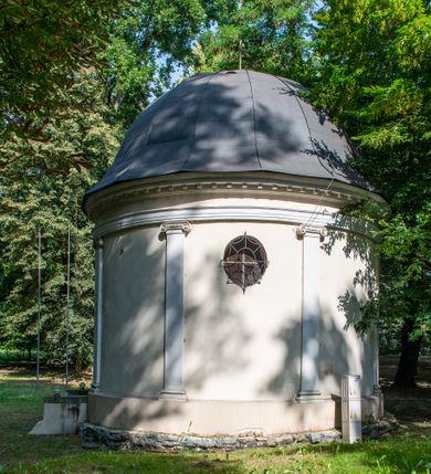 Zdjęcie nr 3: Kaplicę wzniesiono na rzucie koła, nakrywając jej wnętrze półkolistą kopułą. Ściany zewnętrzne zostały podzielone ośmioma pilastrami jońskimi, wspierającymi belkowanie. Powyżej belkowania biegnie profilowany gzyms koronujący, dekorowany fryzem kostkowym. Półokrągłe wejście usytuowano od zachodu. Prowadzi do niego pięć stopni. Wejście zamyka żelazna, klasycystyczna krata. Od wschodu w ścianie przepruto okulus, ujęty od wnętrza półokrągłym glifem w płytkiej, prostokątnej niszy zamkniętej półokrągło. Wnętrze pokryto ochrową polichromią, z wymalowanym białą kreską podziałem odzwierciedlającym artykulację zewnętrzną. Na ścianie umieszczono dwie czworoboczne płyty upamiętniające zmarłych pochowanych w krypcie. Wejście do krypty zamyka prostokątna, marmurowa płyta dekorowana aplikacją ze złoconego brązu, ukazującą trupią czaszkę ze skrzyżowanymi piszczelami umieszczoną nad antabą.