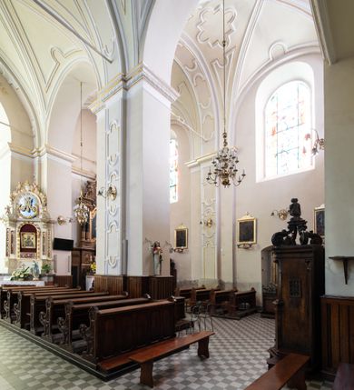 Zdjęcie nr 26: Kościół Wniebowzięcia Najświętszej Marii Panny w Oświęcimu jest świątynia murowaną, orientowaną. Dwuprzęsłowe prezbiterium zamknięte ścianą prostą wzniesiono na rzucie prostokąta. W jego narożach widoczne są przypory. Od południa wybudowano przy nim zakrystię, a od północy kaplicę Chrystusa Ukrzyżowanego, którą gruntownie przebudowano w stylu pseudoromańskim w latach dwudziestych XX wieku. Korpus kościoła uzyskał układ trójnawowej, dwuprzęsłowej hali. Od zachodu na osi wzniesiono czworoboczną, dwupoziomową wieżę. Pierwszy poziom, w którym urządzono kruchtę, jest zaopatrzony w narożach w uskokowe przypory. Natomiast drugi, wyraźnie zmniejszony, został wzniesiony ponad profilowanym gzymsem na rzucie czworobocznym o ściętych narożach. Całość nakryto ostrosłupowym hełmem zwieńczonym krzyżem, wspartym na trójkątnych przyczółkach stanowiących zakończenie ścian drugiego poziomu. Nawa główna otwiera się do naw bocznych z każdej strony poprzez dwiema opilastrowanymi arkadami filarowymi. Tęcza pomiędzy nawą, a prezbiterium uzyskała wykrój półkolisty. Wnetrze obu części kościoła nakryto sklepieniem kolebkowym z lunetami wsparte na gurtach. W części zachodniej kościoła na długości całego korpusu urządzono chór muzyczny wsparty na trzech arkadach z parapetem wygiętym łukowo pośrodku. Sklepienie i parapet chóru zostały udekorowane figurami geometrycznymi ze stiukowych listw profilowanych. Do południowej nawy bocznej prowadzi gotycki, ostrołukowy portal kamienny. Z kolei wejście do prezbiterium z zakrystii oraz z kruchty do północnej nawy bocznej obramieniają dwa prostokątne, kamienne portale gotycko-renesansowe. W prezbiterium ustawiono ołtarz główny, a dwa ołtarze boczne na wschodniej ścianie naw bocznych. Kolejny ołtarz boczny znalazł się po prawej stronie łuku tęczowego. Po jego zaś drugiej stronie zawieszono ambonę. 