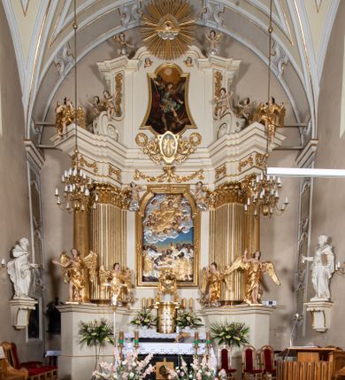 Zdjęcie nr 30: Kościół Wniebowzięcia Najświętszej Marii Panny w Oświęcimu jest świątynia murowaną, orientowaną. Dwuprzęsłowe prezbiterium zamknięte ścianą prostą wzniesiono na rzucie prostokąta. W jego narożach widoczne są przypory. Od południa wybudowano przy nim zakrystię, a od północy kaplicę Chrystusa Ukrzyżowanego, którą gruntownie przebudowano w stylu pseudoromańskim w latach dwudziestych XX wieku. Korpus kościoła uzyskał układ trójnawowej, dwuprzęsłowej hali. Od zachodu na osi wzniesiono czworoboczną, dwupoziomową wieżę. Pierwszy poziom, w którym urządzono kruchtę, jest zaopatrzony w narożach w uskokowe przypory. Natomiast drugi, wyraźnie zmniejszony, został wzniesiony ponad profilowanym gzymsem na rzucie czworobocznym o ściętych narożach. Całość nakryto ostrosłupowym hełmem zwieńczonym krzyżem, wspartym na trójkątnych przyczółkach stanowiących zakończenie ścian drugiego poziomu. Nawa główna otwiera się do naw bocznych z każdej strony poprzez dwiema opilastrowanymi arkadami filarowymi. Tęcza pomiędzy nawą, a prezbiterium uzyskała wykrój półkolisty. Wnetrze obu części kościoła nakryto sklepieniem kolebkowym z lunetami wsparte na gurtach. W części zachodniej kościoła na długości całego korpusu urządzono chór muzyczny wsparty na trzech arkadach z parapetem wygiętym łukowo pośrodku. Sklepienie i parapet chóru zostały udekorowane figurami geometrycznymi ze stiukowych listw profilowanych. Do południowej nawy bocznej prowadzi gotycki, ostrołukowy portal kamienny. Z kolei wejście do prezbiterium z zakrystii oraz z kruchty do północnej nawy bocznej obramieniają dwa prostokątne, kamienne portale gotycko-renesansowe. W prezbiterium ustawiono ołtarz główny, a dwa ołtarze boczne na wschodniej ścianie naw bocznych. Kolejny ołtarz boczny znalazł się po prawej stronie łuku tęczowego. Po jego zaś drugiej stronie zawieszono ambonę. 