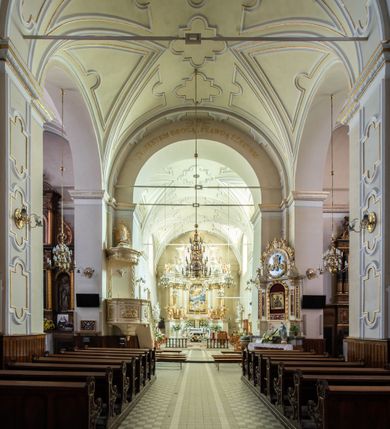 Zdjęcie nr 23: Kościół Wniebowzięcia Najświętszej Marii Panny w Oświęcimu jest świątynia murowaną, orientowaną. Dwuprzęsłowe prezbiterium zamknięte ścianą prostą wzniesiono na rzucie prostokąta. W jego narożach widoczne są przypory. Od południa wybudowano przy nim zakrystię, a od północy kaplicę Chrystusa Ukrzyżowanego, którą gruntownie przebudowano w stylu pseudoromańskim w latach dwudziestych XX wieku. Korpus kościoła uzyskał układ trójnawowej, dwuprzęsłowej hali. Od zachodu na osi wzniesiono czworoboczną, dwupoziomową wieżę. Pierwszy poziom, w którym urządzono kruchtę, jest zaopatrzony w narożach w uskokowe przypory. Natomiast drugi, wyraźnie zmniejszony, został wzniesiony ponad profilowanym gzymsem na rzucie czworobocznym o ściętych narożach. Całość nakryto ostrosłupowym hełmem zwieńczonym krzyżem, wspartym na trójkątnych przyczółkach stanowiących zakończenie ścian drugiego poziomu. Nawa główna otwiera się do naw bocznych z każdej strony poprzez dwiema opilastrowanymi arkadami filarowymi. Tęcza pomiędzy nawą, a prezbiterium uzyskała wykrój półkolisty. Wnetrze obu części kościoła nakryto sklepieniem kolebkowym z lunetami wsparte na gurtach. W części zachodniej kościoła na długości całego korpusu urządzono chór muzyczny wsparty na trzech arkadach z parapetem wygiętym łukowo pośrodku. Sklepienie i parapet chóru zostały udekorowane figurami geometrycznymi ze stiukowych listw profilowanych. Do południowej nawy bocznej prowadzi gotycki, ostrołukowy portal kamienny. Z kolei wejście do prezbiterium z zakrystii oraz z kruchty do północnej nawy bocznej obramieniają dwa prostokątne, kamienne portale gotycko-renesansowe. W prezbiterium ustawiono ołtarz główny, a dwa ołtarze boczne na wschodniej ścianie naw bocznych. Kolejny ołtarz boczny znalazł się po prawej stronie łuku tęczowego. Po jego zaś drugiej stronie zawieszono ambonę. 