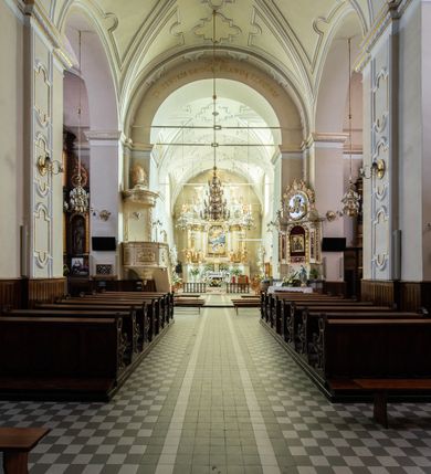 Zdjęcie nr 24: Kościół Wniebowzięcia Najświętszej Marii Panny w Oświęcimu jest świątynia murowaną, orientowaną. Dwuprzęsłowe prezbiterium zamknięte ścianą prostą wzniesiono na rzucie prostokąta. W jego narożach widoczne są przypory. Od południa wybudowano przy nim zakrystię, a od północy kaplicę Chrystusa Ukrzyżowanego, którą gruntownie przebudowano w stylu pseudoromańskim w latach dwudziestych XX wieku. Korpus kościoła uzyskał układ trójnawowej, dwuprzęsłowej hali. Od zachodu na osi wzniesiono czworoboczną, dwupoziomową wieżę. Pierwszy poziom, w którym urządzono kruchtę, jest zaopatrzony w narożach w uskokowe przypory. Natomiast drugi, wyraźnie zmniejszony, został wzniesiony ponad profilowanym gzymsem na rzucie czworobocznym o ściętych narożach. Całość nakryto ostrosłupowym hełmem zwieńczonym krzyżem, wspartym na trójkątnych przyczółkach stanowiących zakończenie ścian drugiego poziomu. Nawa główna otwiera się do naw bocznych z każdej strony poprzez dwiema opilastrowanymi arkadami filarowymi. Tęcza pomiędzy nawą, a prezbiterium uzyskała wykrój półkolisty. Wnetrze obu części kościoła nakryto sklepieniem kolebkowym z lunetami wsparte na gurtach. W części zachodniej kościoła na długości całego korpusu urządzono chór muzyczny wsparty na trzech arkadach z parapetem wygiętym łukowo pośrodku. Sklepienie i parapet chóru zostały udekorowane figurami geometrycznymi ze stiukowych listw profilowanych. Do południowej nawy bocznej prowadzi gotycki, ostrołukowy portal kamienny. Z kolei wejście do prezbiterium z zakrystii oraz z kruchty do północnej nawy bocznej obramieniają dwa prostokątne, kamienne portale gotycko-renesansowe. W prezbiterium ustawiono ołtarz główny, a dwa ołtarze boczne na wschodniej ścianie naw bocznych. Kolejny ołtarz boczny znalazł się po prawej stronie łuku tęczowego. Po jego zaś drugiej stronie zawieszono ambonę. 