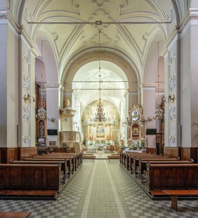 Zdjęcie nr 13: Kościół Wniebowzięcia Najświętszej Marii Panny w Oświęcimu jest świątynia murowaną, orientowaną. Dwuprzęsłowe prezbiterium zamknięte ścianą prostą wzniesiono na rzucie prostokąta. W jego narożach widoczne są przypory. Od południa wybudowano przy nim zakrystię, a od północy kaplicę Chrystusa Ukrzyżowanego, którą gruntownie przebudowano w stylu pseudoromańskim w latach dwudziestych XX wieku. Korpus kościoła uzyskał układ trójnawowej, dwuprzęsłowej hali. Od zachodu na osi wzniesiono czworoboczną, dwupoziomową wieżę. Pierwszy poziom, w którym urządzono kruchtę, jest zaopatrzony w narożach w uskokowe przypory. Natomiast drugi, wyraźnie zmniejszony, został wzniesiony ponad profilowanym gzymsem na rzucie czworobocznym o ściętych narożach. Całość nakryto ostrosłupowym hełmem zwieńczonym krzyżem, wspartym na trójkątnych przyczółkach stanowiących zakończenie ścian drugiego poziomu. Nawa główna otwiera się do naw bocznych z każdej strony poprzez dwiema opilastrowanymi arkadami filarowymi. Tęcza pomiędzy nawą, a prezbiterium uzyskała wykrój półkolisty. Wnetrze obu części kościoła nakryto sklepieniem kolebkowym z lunetami wsparte na gurtach. W części zachodniej kościoła na długości całego korpusu urządzono chór muzyczny wsparty na trzech arkadach z parapetem wygiętym łukowo pośrodku. Sklepienie i parapet chóru zostały udekorowane figurami geometrycznymi ze stiukowych listw profilowanych. Do południowej nawy bocznej prowadzi gotycki, ostrołukowy portal kamienny. Z kolei wejście do prezbiterium z zakrystii oraz z kruchty do północnej nawy bocznej obramieniają dwa prostokątne, kamienne portale gotycko-renesansowe. W prezbiterium ustawiono ołtarz główny, a dwa ołtarze boczne na wschodniej ścianie naw bocznych. Kolejny ołtarz boczny znalazł się po prawej stronie łuku tęczowego. Po jego zaś drugiej stronie zawieszono ambonę. 