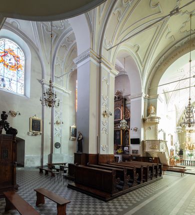 Zdjęcie nr 27: Kościół Wniebowzięcia Najświętszej Marii Panny w Oświęcimu jest świątynia murowaną, orientowaną. Dwuprzęsłowe prezbiterium zamknięte ścianą prostą wzniesiono na rzucie prostokąta. W jego narożach widoczne są przypory. Od południa wybudowano przy nim zakrystię, a od północy kaplicę Chrystusa Ukrzyżowanego, którą gruntownie przebudowano w stylu pseudoromańskim w latach dwudziestych XX wieku. Korpus kościoła uzyskał układ trójnawowej, dwuprzęsłowej hali. Od zachodu na osi wzniesiono czworoboczną, dwupoziomową wieżę. Pierwszy poziom, w którym urządzono kruchtę, jest zaopatrzony w narożach w uskokowe przypory. Natomiast drugi, wyraźnie zmniejszony, został wzniesiony ponad profilowanym gzymsem na rzucie czworobocznym o ściętych narożach. Całość nakryto ostrosłupowym hełmem zwieńczonym krzyżem, wspartym na trójkątnych przyczółkach stanowiących zakończenie ścian drugiego poziomu. Nawa główna otwiera się do naw bocznych z każdej strony poprzez dwiema opilastrowanymi arkadami filarowymi. Tęcza pomiędzy nawą, a prezbiterium uzyskała wykrój półkolisty. Wnetrze obu części kościoła nakryto sklepieniem kolebkowym z lunetami wsparte na gurtach. W części zachodniej kościoła na długości całego korpusu urządzono chór muzyczny wsparty na trzech arkadach z parapetem wygiętym łukowo pośrodku. Sklepienie i parapet chóru zostały udekorowane figurami geometrycznymi ze stiukowych listw profilowanych. Do południowej nawy bocznej prowadzi gotycki, ostrołukowy portal kamienny. Z kolei wejście do prezbiterium z zakrystii oraz z kruchty do północnej nawy bocznej obramieniają dwa prostokątne, kamienne portale gotycko-renesansowe. W prezbiterium ustawiono ołtarz główny, a dwa ołtarze boczne na wschodniej ścianie naw bocznych. Kolejny ołtarz boczny znalazł się po prawej stronie łuku tęczowego. Po jego zaś drugiej stronie zawieszono ambonę. 