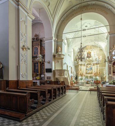 Zdjęcie nr 25: Kościół Wniebowzięcia Najświętszej Marii Panny w Oświęcimu jest świątynia murowaną, orientowaną. Dwuprzęsłowe prezbiterium zamknięte ścianą prostą wzniesiono na rzucie prostokąta. W jego narożach widoczne są przypory. Od południa wybudowano przy nim zakrystię, a od północy kaplicę Chrystusa Ukrzyżowanego, którą gruntownie przebudowano w stylu pseudoromańskim w latach dwudziestych XX wieku. Korpus kościoła uzyskał układ trójnawowej, dwuprzęsłowej hali. Od zachodu na osi wzniesiono czworoboczną, dwupoziomową wieżę. Pierwszy poziom, w którym urządzono kruchtę, jest zaopatrzony w narożach w uskokowe przypory. Natomiast drugi, wyraźnie zmniejszony, został wzniesiony ponad profilowanym gzymsem na rzucie czworobocznym o ściętych narożach. Całość nakryto ostrosłupowym hełmem zwieńczonym krzyżem, wspartym na trójkątnych przyczółkach stanowiących zakończenie ścian drugiego poziomu. Nawa główna otwiera się do naw bocznych z każdej strony poprzez dwiema opilastrowanymi arkadami filarowymi. Tęcza pomiędzy nawą, a prezbiterium uzyskała wykrój półkolisty. Wnetrze obu części kościoła nakryto sklepieniem kolebkowym z lunetami wsparte na gurtach. W części zachodniej kościoła na długości całego korpusu urządzono chór muzyczny wsparty na trzech arkadach z parapetem wygiętym łukowo pośrodku. Sklepienie i parapet chóru zostały udekorowane figurami geometrycznymi ze stiukowych listw profilowanych. Do południowej nawy bocznej prowadzi gotycki, ostrołukowy portal kamienny. Z kolei wejście do prezbiterium z zakrystii oraz z kruchty do północnej nawy bocznej obramieniają dwa prostokątne, kamienne portale gotycko-renesansowe. W prezbiterium ustawiono ołtarz główny, a dwa ołtarze boczne na wschodniej ścianie naw bocznych. Kolejny ołtarz boczny znalazł się po prawej stronie łuku tęczowego. Po jego zaś drugiej stronie zawieszono ambonę. 