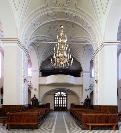 Zdjęcie nr 35: Kościół Wniebowzięcia Najświętszej Marii Panny w Oświęcimu jest świątynia murowaną, orientowaną. Dwuprzęsłowe prezbiterium zamknięte ścianą prostą wzniesiono na rzucie prostokąta. W jego narożach widoczne są przypory. Od południa wybudowano przy nim zakrystię, a od północy kaplicę Chrystusa Ukrzyżowanego, którą gruntownie przebudowano w stylu pseudoromańskim w latach dwudziestych XX wieku. Korpus kościoła uzyskał układ trójnawowej, dwuprzęsłowej hali. Od zachodu na osi wzniesiono czworoboczną, dwupoziomową wieżę. Pierwszy poziom, w którym urządzono kruchtę, jest zaopatrzony w narożach w uskokowe przypory. Natomiast drugi, wyraźnie zmniejszony, został wzniesiony ponad profilowanym gzymsem na rzucie czworobocznym o ściętych narożach. Całość nakryto ostrosłupowym hełmem zwieńczonym krzyżem, wspartym na trójkątnych przyczółkach stanowiących zakończenie ścian drugiego poziomu. Nawa główna otwiera się do naw bocznych z każdej strony poprzez dwiema opilastrowanymi arkadami filarowymi. Tęcza pomiędzy nawą, a prezbiterium uzyskała wykrój półkolisty. Wnetrze obu części kościoła nakryto sklepieniem kolebkowym z lunetami wsparte na gurtach. W części zachodniej kościoła na długości całego korpusu urządzono chór muzyczny wsparty na trzech arkadach z parapetem wygiętym łukowo pośrodku. Sklepienie i parapet chóru zostały udekorowane figurami geometrycznymi ze stiukowych listw profilowanych. Do południowej nawy bocznej prowadzi gotycki, ostrołukowy portal kamienny. Z kolei wejście do prezbiterium z zakrystii oraz z kruchty do północnej nawy bocznej obramieniają dwa prostokątne, kamienne portale gotycko-renesansowe. W prezbiterium ustawiono ołtarz główny, a dwa ołtarze boczne na wschodniej ścianie naw bocznych. Kolejny ołtarz boczny znalazł się po prawej stronie łuku tęczowego. Po jego zaś drugiej stronie zawieszono ambonę. 