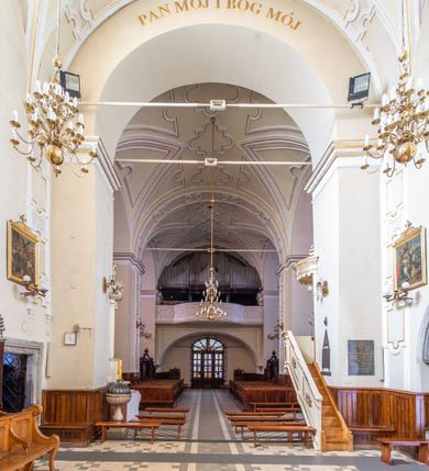 Zdjęcie nr 32: Kościół Wniebowzięcia Najświętszej Marii Panny w Oświęcimu jest świątynia murowaną, orientowaną. Dwuprzęsłowe prezbiterium zamknięte ścianą prostą wzniesiono na rzucie prostokąta. W jego narożach widoczne są przypory. Od południa wybudowano przy nim zakrystię, a od północy kaplicę Chrystusa Ukrzyżowanego, którą gruntownie przebudowano w stylu pseudoromańskim w latach dwudziestych XX wieku. Korpus kościoła uzyskał układ trójnawowej, dwuprzęsłowej hali. Od zachodu na osi wzniesiono czworoboczną, dwupoziomową wieżę. Pierwszy poziom, w którym urządzono kruchtę, jest zaopatrzony w narożach w uskokowe przypory. Natomiast drugi, wyraźnie zmniejszony, został wzniesiony ponad profilowanym gzymsem na rzucie czworobocznym o ściętych narożach. Całość nakryto ostrosłupowym hełmem zwieńczonym krzyżem, wspartym na trójkątnych przyczółkach stanowiących zakończenie ścian drugiego poziomu. Nawa główna otwiera się do naw bocznych z każdej strony poprzez dwiema opilastrowanymi arkadami filarowymi. Tęcza pomiędzy nawą, a prezbiterium uzyskała wykrój półkolisty. Wnetrze obu części kościoła nakryto sklepieniem kolebkowym z lunetami wsparte na gurtach. W części zachodniej kościoła na długości całego korpusu urządzono chór muzyczny wsparty na trzech arkadach z parapetem wygiętym łukowo pośrodku. Sklepienie i parapet chóru zostały udekorowane figurami geometrycznymi ze stiukowych listw profilowanych. Do południowej nawy bocznej prowadzi gotycki, ostrołukowy portal kamienny. Z kolei wejście do prezbiterium z zakrystii oraz z kruchty do północnej nawy bocznej obramieniają dwa prostokątne, kamienne portale gotycko-renesansowe. W prezbiterium ustawiono ołtarz główny, a dwa ołtarze boczne na wschodniej ścianie naw bocznych. Kolejny ołtarz boczny znalazł się po prawej stronie łuku tęczowego. Po jego zaś drugiej stronie zawieszono ambonę. 