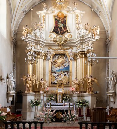 Zdjęcie nr 31: Kościół Wniebowzięcia Najświętszej Marii Panny w Oświęcimu jest świątynia murowaną, orientowaną. Dwuprzęsłowe prezbiterium zamknięte ścianą prostą wzniesiono na rzucie prostokąta. W jego narożach widoczne są przypory. Od południa wybudowano przy nim zakrystię, a od północy kaplicę Chrystusa Ukrzyżowanego, którą gruntownie przebudowano w stylu pseudoromańskim w latach dwudziestych XX wieku. Korpus kościoła uzyskał układ trójnawowej, dwuprzęsłowej hali. Od zachodu na osi wzniesiono czworoboczną, dwupoziomową wieżę. Pierwszy poziom, w którym urządzono kruchtę, jest zaopatrzony w narożach w uskokowe przypory. Natomiast drugi, wyraźnie zmniejszony, został wzniesiony ponad profilowanym gzymsem na rzucie czworobocznym o ściętych narożach. Całość nakryto ostrosłupowym hełmem zwieńczonym krzyżem, wspartym na trójkątnych przyczółkach stanowiących zakończenie ścian drugiego poziomu. Nawa główna otwiera się do naw bocznych z każdej strony poprzez dwiema opilastrowanymi arkadami filarowymi. Tęcza pomiędzy nawą, a prezbiterium uzyskała wykrój półkolisty. Wnetrze obu części kościoła nakryto sklepieniem kolebkowym z lunetami wsparte na gurtach. W części zachodniej kościoła na długości całego korpusu urządzono chór muzyczny wsparty na trzech arkadach z parapetem wygiętym łukowo pośrodku. Sklepienie i parapet chóru zostały udekorowane figurami geometrycznymi ze stiukowych listw profilowanych. Do południowej nawy bocznej prowadzi gotycki, ostrołukowy portal kamienny. Z kolei wejście do prezbiterium z zakrystii oraz z kruchty do północnej nawy bocznej obramieniają dwa prostokątne, kamienne portale gotycko-renesansowe. W prezbiterium ustawiono ołtarz główny, a dwa ołtarze boczne na wschodniej ścianie naw bocznych. Kolejny ołtarz boczny znalazł się po prawej stronie łuku tęczowego. Po jego zaś drugiej stronie zawieszono ambonę. 