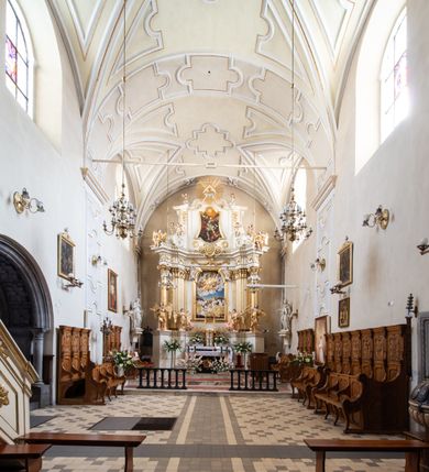 Zdjęcie nr 29: Kościół Wniebowzięcia Najświętszej Marii Panny w Oświęcimu jest świątynia murowaną, orientowaną. Dwuprzęsłowe prezbiterium zamknięte ścianą prostą wzniesiono na rzucie prostokąta. W jego narożach widoczne są przypory. Od południa wybudowano przy nim zakrystię, a od północy kaplicę Chrystusa Ukrzyżowanego, którą gruntownie przebudowano w stylu pseudoromańskim w latach dwudziestych XX wieku. Korpus kościoła uzyskał układ trójnawowej, dwuprzęsłowej hali. Od zachodu na osi wzniesiono czworoboczną, dwupoziomową wieżę. Pierwszy poziom, w którym urządzono kruchtę, jest zaopatrzony w narożach w uskokowe przypory. Natomiast drugi, wyraźnie zmniejszony, został wzniesiony ponad profilowanym gzymsem na rzucie czworobocznym o ściętych narożach. Całość nakryto ostrosłupowym hełmem zwieńczonym krzyżem, wspartym na trójkątnych przyczółkach stanowiących zakończenie ścian drugiego poziomu. Nawa główna otwiera się do naw bocznych z każdej strony poprzez dwiema opilastrowanymi arkadami filarowymi. Tęcza pomiędzy nawą, a prezbiterium uzyskała wykrój półkolisty. Wnetrze obu części kościoła nakryto sklepieniem kolebkowym z lunetami wsparte na gurtach. W części zachodniej kościoła na długości całego korpusu urządzono chór muzyczny wsparty na trzech arkadach z parapetem wygiętym łukowo pośrodku. Sklepienie i parapet chóru zostały udekorowane figurami geometrycznymi ze stiukowych listw profilowanych. Do południowej nawy bocznej prowadzi gotycki, ostrołukowy portal kamienny. Z kolei wejście do prezbiterium z zakrystii oraz z kruchty do północnej nawy bocznej obramieniają dwa prostokątne, kamienne portale gotycko-renesansowe. W prezbiterium ustawiono ołtarz główny, a dwa ołtarze boczne na wschodniej ścianie naw bocznych. Kolejny ołtarz boczny znalazł się po prawej stronie łuku tęczowego. Po jego zaś drugiej stronie zawieszono ambonę. 