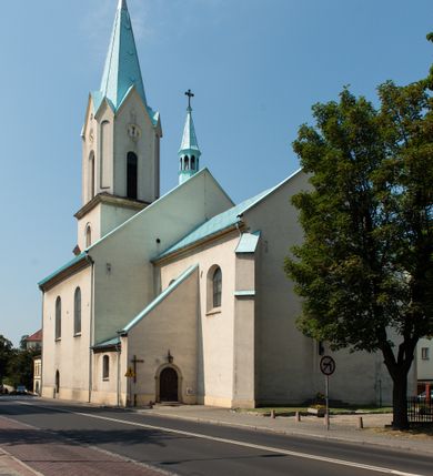 Zdjęcie nr 8: Kościół Wniebowzięcia Najświętszej Marii Panny w Oświęcimu jest świątynia murowaną, orientowaną. Dwuprzęsłowe prezbiterium zamknięte ścianą prostą wzniesiono na rzucie prostokąta. W jego narożach widoczne są przypory. Od południa wybudowano przy nim zakrystię, a od północy kaplicę Chrystusa Ukrzyżowanego, którą gruntownie przebudowano w stylu pseudoromańskim w latach dwudziestych XX wieku. Korpus kościoła uzyskał układ trójnawowej, dwuprzęsłowej hali. Od zachodu na osi wzniesiono czworoboczną, dwupoziomową wieżę. Pierwszy poziom, w którym urządzono kruchtę, jest zaopatrzony w narożach w uskokowe przypory. Natomiast drugi, wyraźnie zmniejszony, został wzniesiony ponad profilowanym gzymsem na rzucie czworobocznym o ściętych narożach. Całość nakryto ostrosłupowym hełmem zwieńczonym krzyżem, wspartym na trójkątnych przyczółkach stanowiących zakończenie ścian drugiego poziomu. Nawa główna otwiera się do naw bocznych z każdej strony poprzez dwiema opilastrowanymi arkadami filarowymi. Tęcza pomiędzy nawą, a prezbiterium uzyskała wykrój półkolisty. Wnetrze obu części kościoła nakryto sklepieniem kolebkowym z lunetami wsparte na gurtach. W części zachodniej kościoła na długości całego korpusu urządzono chór muzyczny wsparty na trzech arkadach z parapetem wygiętym łukowo pośrodku. Sklepienie i parapet chóru zostały udekorowane figurami geometrycznymi ze stiukowych listw profilowanych. Do południowej nawy bocznej prowadzi gotycki, ostrołukowy portal kamienny. Z kolei wejście do prezbiterium z zakrystii oraz z kruchty do północnej nawy bocznej obramieniają dwa prostokątne, kamienne portale gotycko-renesansowe. W prezbiterium ustawiono ołtarz główny, a dwa ołtarze boczne na wschodniej ścianie naw bocznych. Kolejny ołtarz boczny znalazł się po prawej stronie łuku tęczowego. Po jego zaś drugiej stronie zawieszono ambonę. 