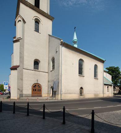 Zdjęcie nr 46: Kościół Wniebowzięcia Najświętszej Marii Panny w Oświęcimu jest świątynia murowaną, orientowaną. Dwuprzęsłowe prezbiterium zamknięte ścianą prostą wzniesiono na rzucie prostokąta. W jego narożach widoczne są przypory. Od południa wybudowano przy nim zakrystię, a od północy kaplicę Chrystusa Ukrzyżowanego, którą gruntownie przebudowano w stylu pseudoromańskim w latach dwudziestych XX wieku. Korpus kościoła uzyskał układ trójnawowej, dwuprzęsłowej hali. Od zachodu na osi wzniesiono czworoboczną, dwupoziomową wieżę. Pierwszy poziom, w którym urządzono kruchtę, jest zaopatrzony w narożach w uskokowe przypory. Natomiast drugi, wyraźnie zmniejszony, został wzniesiony ponad profilowanym gzymsem na rzucie czworobocznym o ściętych narożach. Całość nakryto ostrosłupowym hełmem zwieńczonym krzyżem, wspartym na trójkątnych przyczółkach stanowiących zakończenie ścian drugiego poziomu. Nawa główna otwiera się do naw bocznych z każdej strony poprzez dwiema opilastrowanymi arkadami filarowymi. Tęcza pomiędzy nawą, a prezbiterium uzyskała wykrój półkolisty. Wnetrze obu części kościoła nakryto sklepieniem kolebkowym z lunetami wsparte na gurtach. W części zachodniej kościoła na długości całego korpusu urządzono chór muzyczny wsparty na trzech arkadach z parapetem wygiętym łukowo pośrodku. Sklepienie i parapet chóru zostały udekorowane figurami geometrycznymi ze stiukowych listw profilowanych. Do południowej nawy bocznej prowadzi gotycki, ostrołukowy portal kamienny. Z kolei wejście do prezbiterium z zakrystii oraz z kruchty do północnej nawy bocznej obramieniają dwa prostokątne, kamienne portale gotycko-renesansowe. W prezbiterium ustawiono ołtarz główny, a dwa ołtarze boczne na wschodniej ścianie naw bocznych. Kolejny ołtarz boczny znalazł się po prawej stronie łuku tęczowego. Po jego zaś drugiej stronie zawieszono ambonę. 