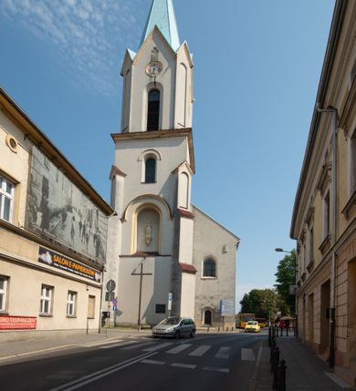 Zdjęcie nr 47: Kościół Wniebowzięcia Najświętszej Marii Panny w Oświęcimu jest świątynia murowaną, orientowaną. Dwuprzęsłowe prezbiterium zamknięte ścianą prostą wzniesiono na rzucie prostokąta. W jego narożach widoczne są przypory. Od południa wybudowano przy nim zakrystię, a od północy kaplicę Chrystusa Ukrzyżowanego, którą gruntownie przebudowano w stylu pseudoromańskim w latach dwudziestych XX wieku. Korpus kościoła uzyskał układ trójnawowej, dwuprzęsłowej hali. Od zachodu na osi wzniesiono czworoboczną, dwupoziomową wieżę. Pierwszy poziom, w którym urządzono kruchtę, jest zaopatrzony w narożach w uskokowe przypory. Natomiast drugi, wyraźnie zmniejszony, został wzniesiony ponad profilowanym gzymsem na rzucie czworobocznym o ściętych narożach. Całość nakryto ostrosłupowym hełmem zwieńczonym krzyżem, wspartym na trójkątnych przyczółkach stanowiących zakończenie ścian drugiego poziomu. Nawa główna otwiera się do naw bocznych z każdej strony poprzez dwiema opilastrowanymi arkadami filarowymi. Tęcza pomiędzy nawą, a prezbiterium uzyskała wykrój półkolisty. Wnetrze obu części kościoła nakryto sklepieniem kolebkowym z lunetami wsparte na gurtach. W części zachodniej kościoła na długości całego korpusu urządzono chór muzyczny wsparty na trzech arkadach z parapetem wygiętym łukowo pośrodku. Sklepienie i parapet chóru zostały udekorowane figurami geometrycznymi ze stiukowych listw profilowanych. Do południowej nawy bocznej prowadzi gotycki, ostrołukowy portal kamienny. Z kolei wejście do prezbiterium z zakrystii oraz z kruchty do północnej nawy bocznej obramieniają dwa prostokątne, kamienne portale gotycko-renesansowe. W prezbiterium ustawiono ołtarz główny, a dwa ołtarze boczne na wschodniej ścianie naw bocznych. Kolejny ołtarz boczny znalazł się po prawej stronie łuku tęczowego. Po jego zaś drugiej stronie zawieszono ambonę. 