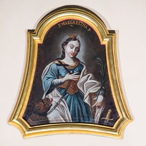 Zdjęcie nr 1: Obraz w profilowanej, złoconej ramie o kształcie wklęsło-wypukłym z przedstawieniem św. Małgorzaty. Święta została ukazana do wysokości trzech czwartych, zwrócona w lewo, ze spuszczonym wzrokiem. W prawej uniesionej ręce ma krzyż oraz łańcuch, na którym trzyma niewielkiego smoka. Lewą rękę z palmą męczeństwa odsuwa do boku. Ma okrągłą twarz, z dużymi, półprzymkniętymi oczami, długim nosem, niewielkimi ustami i odznaczającym się podbródkiem. Włosy z przedziałkiem zostały zaczesane do tyłu i ozdobione sznurami pereł, na głowie ma niewielką koronę. Jest ubrana w niebieską suknię ze złotym lamowaniem przy dekolcie i złoty gorset. Narzucony jasny płaszcz zakrywa plecy, lewą rękę i prawą nogę. W lewym dolnym rogu obrazu widać fragment brązowego smoka z otwartą paszczą, z której sterczą białe zęby i język. Stwór spogląda na Małgorzatę, na szyi ma obrożę, od której odchodzi łańcuch. W prawym dolnym rogu widoczny fragment miecza, przy jego rękojeści napis „1905 / odnow[...]” . Tło obrazu jest jednolite, ciemnobrązowe, rozświetlone jedynie za głową świętej. U góry, tuż poniżej krawędzi ramy napis „S(ANCTA) MARGARETHA. p. / m.”. 