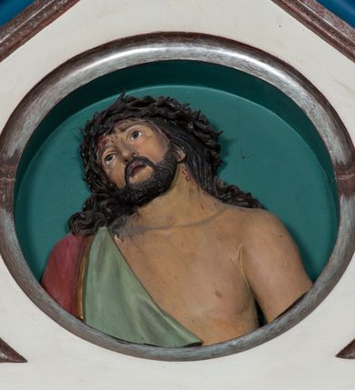 Zdjęcie nr 9: Ołtarz architektoniczny, przyścienny, jednokondygnacyjny, trójosiowy, ze zwieńczeniem. Ołtarz prostopadłościenny z antepedium zdobionym polichromowanym motywem liści akantu po bokach, pośrodku medalion z monogramem chrystologicznym. Tabernakulum w formie prostopadłościennej szafki z drzwiczkami zamkniętymi łukiem półkolistym ujętym fryzem arkadkowym, zdobionych monogramem chrystologicznym. Retabulum na niewysokim, zryzalitowanym cokole o zakończeniach w formie konsoli. Osi głównej części nastawy są w formie półkolistych arkad z niszami, wspartych parami kolumn o kapitelach kompozytowych, przy czym środkowa jest większa względem bocznych dźwigających belkowanie. Zwieńczenie części środkowej retabulum przybiera formę zbliżoną do trójkątnego przyczółka. Pola cokołu retabulum zdobi polichromowana i płaskorzeźbiona ornamentyka roślinna. Ścianki niszy pokryte są dekoracją malarską naśladującą wzorzyste tkaniny, a w górnej partii błękitne, gwieździste niebo. Łuki nisz ujmuje ażurowy fryz arkadkowy, dodatkowo obramienie niszy głównej z motywem rozetek. W przyłuczach dekoracja w formie wici roślinnej. Krawędź attyki oraz zwieńczenia zdobi ażurowa wić roślinna. W polu części środkowej znajduje się figura Madonny z Dzieciątkiem, w arkadzie po prawej stronie ołtarza św. Andrzeja, po lewej św. Piotra. Struktura ołtarza utrzymana jest w kolorach białym, niebieskim, zielonym i jasnoczerwonym, detal architektoniczny i ornamentyka są złocone.        