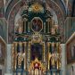 Zdjęcie nr 1: Nastawa architektoniczna, trójosiowa, dwukondygnacyjna, ustawiona na wysokim cokole z wyodrębnionymi prostopadłościanami. Ołtarz prostopadłościenny, z drewnianą mensą. Antepedium ujęte profilowaną ramą, w polu medalion z monogramem IHS w glorii. Na ołtarzu ustawione tabernakulum z tronem wystawienia. Tabernakulum w formie trójosiowej skrzynki, o wklęsło-wypukłym licu, artykułowanej kolumienkami o kręconych trzonach, podtrzymującymi belkowanie, wyłamane na ich osi, z gzymsem wyłamanym faliście na osi środkowej. Drzwiczki w formie stojącego prostokąta zamkniętego łukiem półkolistym nadwieszonym z uskokiem, ujętego ramą z płaskorzeźbionym przedstawieniem kielicha z hostią w glorii. Na osiach bocznych płaskorzeźbione przedstawienia winnego grona. Tron wystawienia w formie paludamentu, podwójnie podwieszonego po bokach, zwieńczonego koroną zamkniętą. 
Cokół dekorowany płycinami wypełnionymi suchym akantem. Pierwsza kondygnacja nastawy ujęta dwiema parami kolumn o kapitelach kompozytowych oraz stojącą między nimi parą pilastrów, w których trzonach znajdują się gabloty na wota. Przed pilastrami na cokołach ustawione dwie figury aniołów. Podpory dźwigają pełne belkowanie, przerwane w partii architrawu i fryzu nad polem środkowym, wyłamane na osi kolumn, na osi pilastrów belkowanie wyłamane pod kątem, w formie impostu z podwieszonymi szyszkami. Na belkowaniu, na obłokach dwie figurki adorujących puttów oraz dwa wazony na cokołach. W polu środkowym wnęka w formie stojącego prostokąta o wciętych górnych narożach, ujęta podwójną ramą, dekorowaną ornamentem roślinnym, z obrazem św. Józefa. Wnęka otoczona z trzech stron gablotami z wotami. Nad nią, w polu belkowania kartusz utworzony z suchego akantu z napisem w polu: „ŚW(IĘTY) JÓZEFIE / MÓDL SIĘ / ZA NAMI”. Druga kondygnacja o szerokości osi środkowej, ustawiona na cokole z wyodrębnionymi prostopadłościanami oraz gablotą z wotami, ujęta dwiema parami pilastrów i spływami wolutowymi oraz stojącą przed nimi parą kolumn, dźwigających zdwojone imposty oraz fragmenty przerwanego, półkolistego przyczółka z siedzącymi puttami. Spływy zdobione festonami utworzonymi z wstęgi oraz kwiatów. Całość zamknięta fragmentem falistego gzymsu oraz Okiem Opatrzności w glorii promienistej. W polu obraz Zaślubin Marii ze św. Józefem w formie stojącego prostokąta o ściętych narożach, ujęty ramą dekorowaną ornamentem roślinnym. Flankowany dwiema prostokątnymi płycinami wypełnionymi akantem. Obie kondygnacje ujęte uszami utworzonymi z suchego akantu. Struktura polichromowana w kolorze zielonym, kolumny, ornamentyka i profile złocone.




