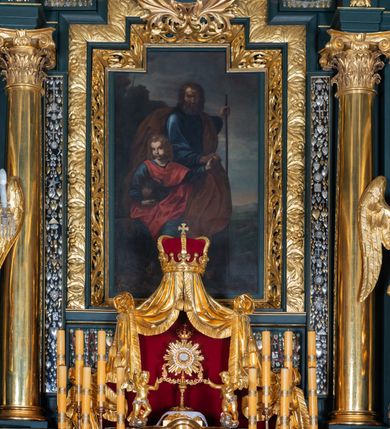 Zdjęcie nr 3: Nastawa architektoniczna, trójosiowa, dwukondygnacyjna, ustawiona na wysokim cokole z wyodrębnionymi prostopadłościanami. Ołtarz prostopadłościenny, z drewnianą mensą. Antepedium ujęte profilowaną ramą, w polu medalion z monogramem IHS w glorii. Na ołtarzu ustawione tabernakulum z tronem wystawienia. Tabernakulum w formie trójosiowej skrzynki, o wklęsło-wypukłym licu, artykułowanej kolumienkami o kręconych trzonach, podtrzymującymi belkowanie, wyłamane na ich osi, z gzymsem wyłamanym faliście na osi środkowej. Drzwiczki w formie stojącego prostokąta zamkniętego łukiem półkolistym nadwieszonym z uskokiem, ujętego ramą z płaskorzeźbionym przedstawieniem kielicha z hostią w glorii. Na osiach bocznych płaskorzeźbione przedstawienia winnego grona. Tron wystawienia w formie paludamentu, podwójnie podwieszonego po bokach, zwieńczonego koroną zamkniętą. 
Cokół dekorowany płycinami wypełnionymi suchym akantem. Pierwsza kondygnacja nastawy ujęta dwiema parami kolumn o kapitelach kompozytowych oraz stojącą między nimi parą pilastrów, w których trzonach znajdują się gabloty na wota. Przed pilastrami na cokołach ustawione dwie figury aniołów. Podpory dźwigają pełne belkowanie, przerwane w partii architrawu i fryzu nad polem środkowym, wyłamane na osi kolumn, na osi pilastrów belkowanie wyłamane pod kątem, w formie impostu z podwieszonymi szyszkami. Na belkowaniu, na obłokach dwie figurki adorujących puttów oraz dwa wazony na cokołach. W polu środkowym wnęka w formie stojącego prostokąta o wciętych górnych narożach, ujęta podwójną ramą, dekorowaną ornamentem roślinnym, z obrazem św. Józefa. Wnęka otoczona z trzech stron gablotami z wotami. Nad nią, w polu belkowania kartusz utworzony z suchego akantu z napisem w polu: „ŚW(IĘTY) JÓZEFIE / MÓDL SIĘ / ZA NAMI”. Druga kondygnacja o szerokości osi środkowej, ustawiona na cokole z wyodrębnionymi prostopadłościanami oraz gablotą z wotami, ujęta dwiema parami pilastrów i spływami wolutowymi oraz stojącą przed nimi parą kolumn, dźwigających zdwojone imposty oraz fragmenty przerwanego, półkolistego przyczółka z siedzącymi puttami. Spływy zdobione festonami utworzonymi z wstęgi oraz kwiatów. Całość zamknięta fragmentem falistego gzymsu oraz Okiem Opatrzności w glorii promienistej. W polu obraz Zaślubin Marii ze św. Józefem w formie stojącego prostokąta o ściętych narożach, ujęty ramą dekorowaną ornamentem roślinnym. Flankowany dwiema prostokątnymi płycinami wypełnionymi akantem. Obie kondygnacje ujęte uszami utworzonymi z suchego akantu. Struktura polichromowana w kolorze zielonym, kolumny, ornamentyka i profile złocone.




