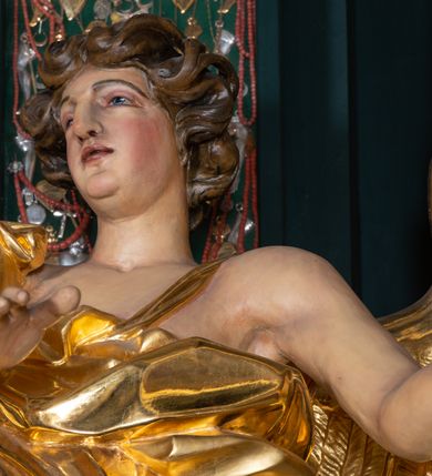 Zdjęcie nr 14: Nastawa architektoniczna, trójosiowa, dwukondygnacyjna, ustawiona na wysokim cokole z wyodrębnionymi prostopadłościanami. Ołtarz prostopadłościenny, z drewnianą mensą. Antepedium ujęte profilowaną ramą, w polu medalion z monogramem IHS w glorii. Na ołtarzu ustawione tabernakulum z tronem wystawienia. Tabernakulum w formie trójosiowej skrzynki, o wklęsło-wypukłym licu, artykułowanej kolumienkami o kręconych trzonach, podtrzymującymi belkowanie, wyłamane na ich osi, z gzymsem wyłamanym faliście na osi środkowej. Drzwiczki w formie stojącego prostokąta zamkniętego łukiem półkolistym nadwieszonym z uskokiem, ujętego ramą z płaskorzeźbionym przedstawieniem kielicha z hostią w glorii. Na osiach bocznych płaskorzeźbione przedstawienia winnego grona. Tron wystawienia w formie paludamentu, podwójnie podwieszonego po bokach, zwieńczonego koroną zamkniętą. 
Cokół dekorowany płycinami wypełnionymi suchym akantem. Pierwsza kondygnacja nastawy ujęta dwiema parami kolumn o kapitelach kompozytowych oraz stojącą między nimi parą pilastrów, w których trzonach znajdują się gabloty na wota. Przed pilastrami na cokołach ustawione dwie figury aniołów. Podpory dźwigają pełne belkowanie, przerwane w partii architrawu i fryzu nad polem środkowym, wyłamane na osi kolumn, na osi pilastrów belkowanie wyłamane pod kątem, w formie impostu z podwieszonymi szyszkami. Na belkowaniu, na obłokach dwie figurki adorujących puttów oraz dwa wazony na cokołach. W polu środkowym wnęka w formie stojącego prostokąta o wciętych górnych narożach, ujęta podwójną ramą, dekorowaną ornamentem roślinnym, z obrazem św. Józefa. Wnęka otoczona z trzech stron gablotami z wotami. Nad nią, w polu belkowania kartusz utworzony z suchego akantu z napisem w polu: „ŚW(IĘTY) JÓZEFIE / MÓDL SIĘ / ZA NAMI”. Druga kondygnacja o szerokości osi środkowej, ustawiona na cokole z wyodrębnionymi prostopadłościanami oraz gablotą z wotami, ujęta dwiema parami pilastrów i spływami wolutowymi oraz stojącą przed nimi parą kolumn, dźwigających zdwojone imposty oraz fragmenty przerwanego, półkolistego przyczółka z siedzącymi puttami. Spływy zdobione festonami utworzonymi z wstęgi oraz kwiatów. Całość zamknięta fragmentem falistego gzymsu oraz Okiem Opatrzności w glorii promienistej. W polu obraz Zaślubin Marii ze św. Józefem w formie stojącego prostokąta o ściętych narożach, ujęty ramą dekorowaną ornamentem roślinnym. Flankowany dwiema prostokątnymi płycinami wypełnionymi akantem. Obie kondygnacje ujęte uszami utworzonymi z suchego akantu. Struktura polichromowana w kolorze zielonym, kolumny, ornamentyka i profile złocone.




